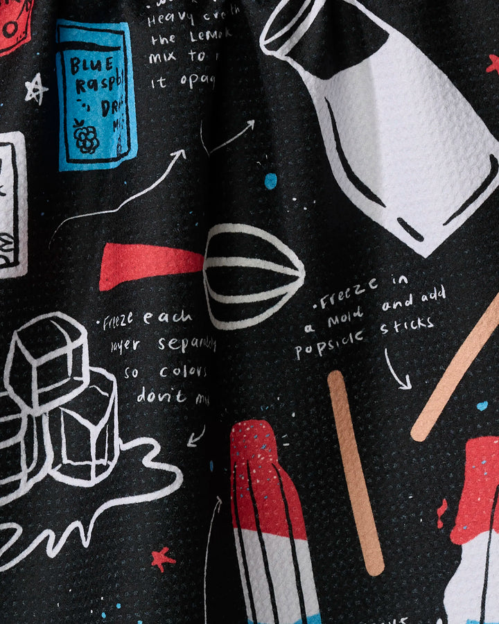 The "Popsicles" tea towel by Janna Sue Design features colorful drawings of ice cubes, a bottle, whisk, popsicle sticks, and a blue raspberry drink mix packet with handwritten instructions—made from quick-drying recycled materials.