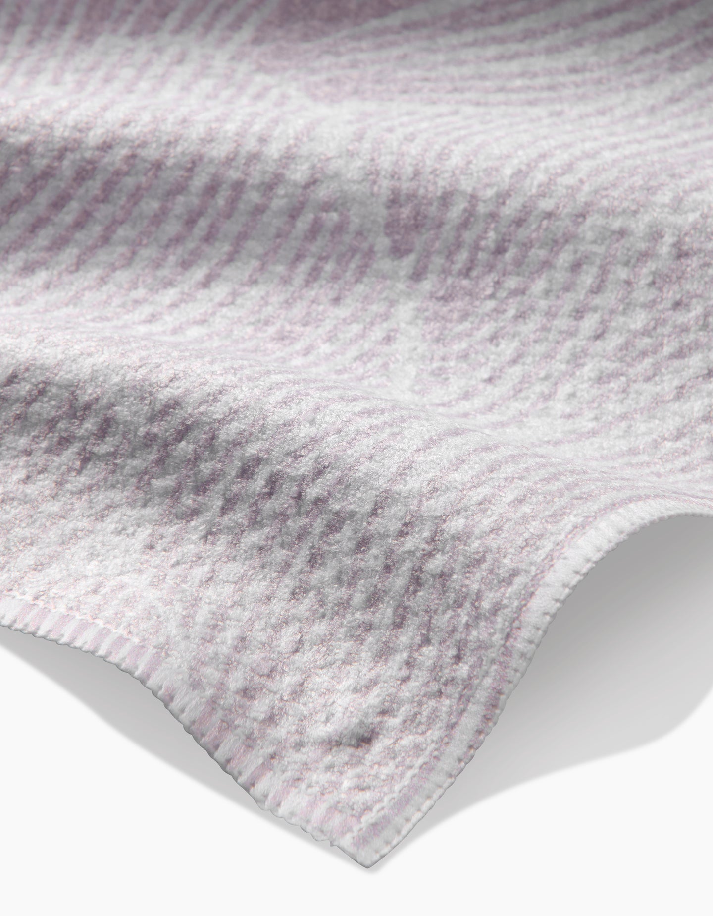 A close-up of the Geometry Posh Petals Blushed Bergamot kitchen towel, featuring a soft, textured design in light purple and white with gentle folds and slightly wavy edges.