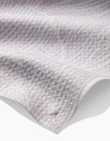 A close-up of the Geometry Posh Petals Blushed Bergamot kitchen towel, featuring a soft, textured design in light purple and white with gentle folds and slightly wavy edges.