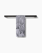 A black towel bar holds the Geometry Posh Petals Fresh Linen quick-drying towel, featuring an abstract black-and-white wavy line pattern, against a plain white background.