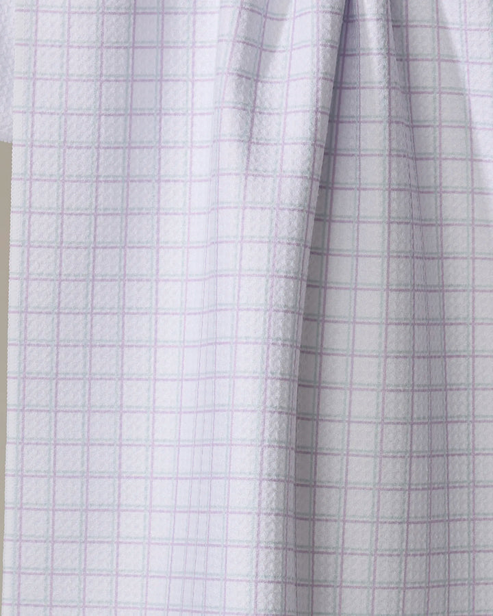 Close-up of The Buy Guide’s Preppy - Mint Lilac tea towel, featuring a white base with a light purple grid pattern. The ultra-absorbent fabric drapes softly, showing geometric lines vertically and horizontally across the material.