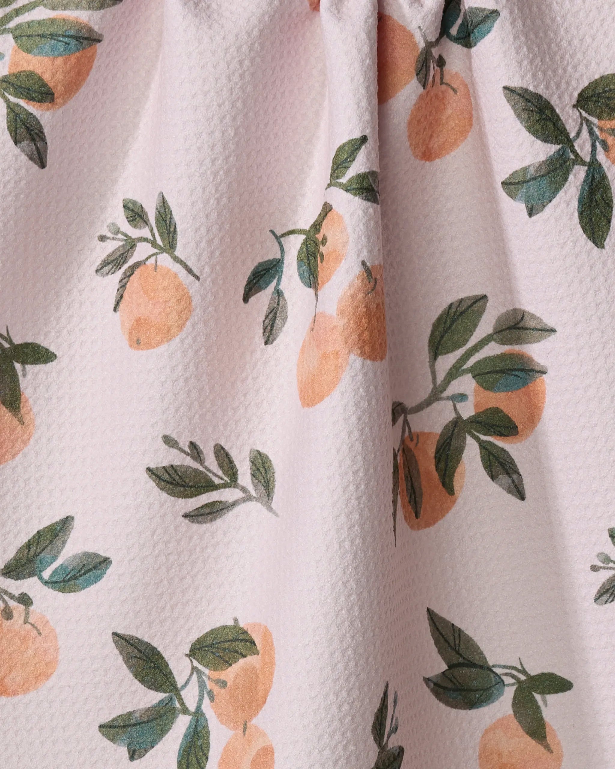 A close-up of Pretty In Peach by Janna Sue Design shows pink textured fabric made from recycled materials, adorned with illustrated oranges and green leaves.