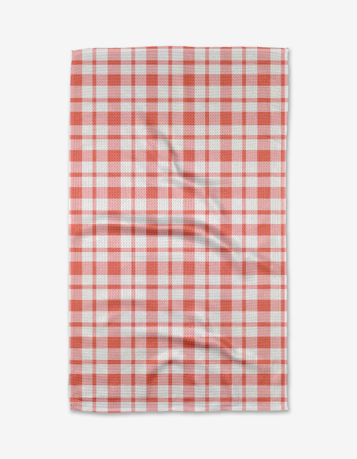 The Pretty in Pink Plaid tea towel by Charlie Rowan Designs is made from recycled materials, features a pink checkered pattern, and is shown flat with slight wrinkles on its quick-drying fabric.