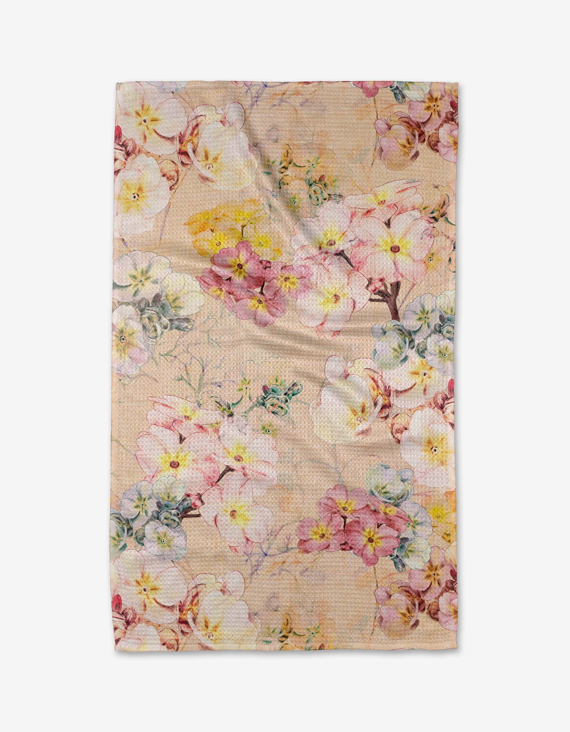 The Primroses tea towel by Pascale Dilger features pink, yellow, and white flowers with green leaves on a light beige background. Made from recycled materials, the slightly wrinkled fabric is shown on a plain white surface.