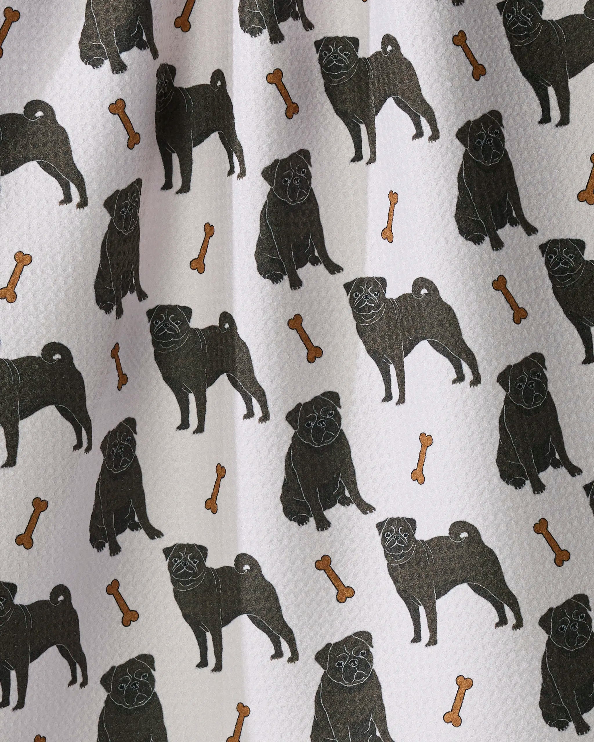 Pug Club by Geometry features a playful pattern of black pugs in various poses with scattered brown dog bones on a white textured background, making it the perfect charming kitchen or tea towel crafted from recycled materials.