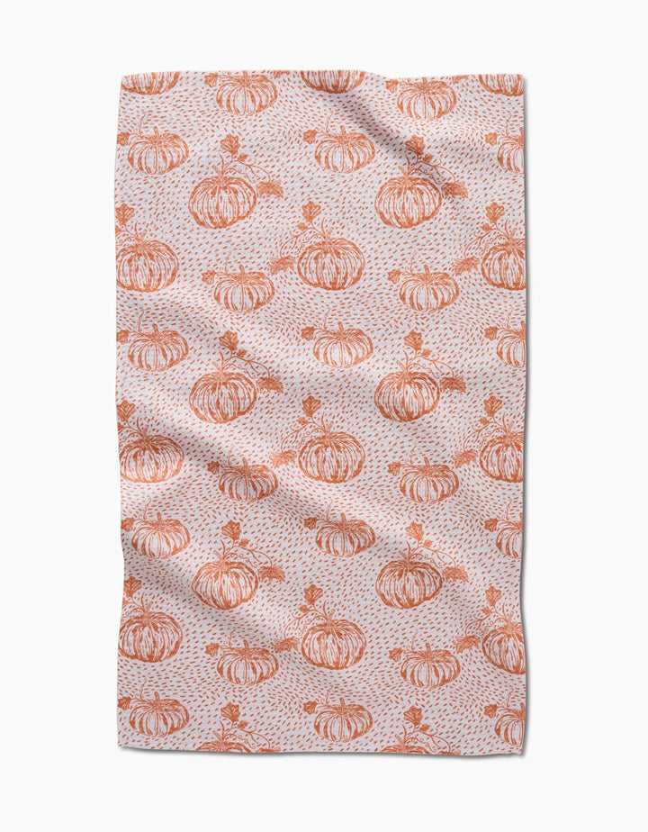 Pumpkin Field by Charlie Rowan Designs is a tea towel with hand-drawn orange pumpkins, leaves, and abstract speckles on a light background—perfect for adding charm to your kitchen.