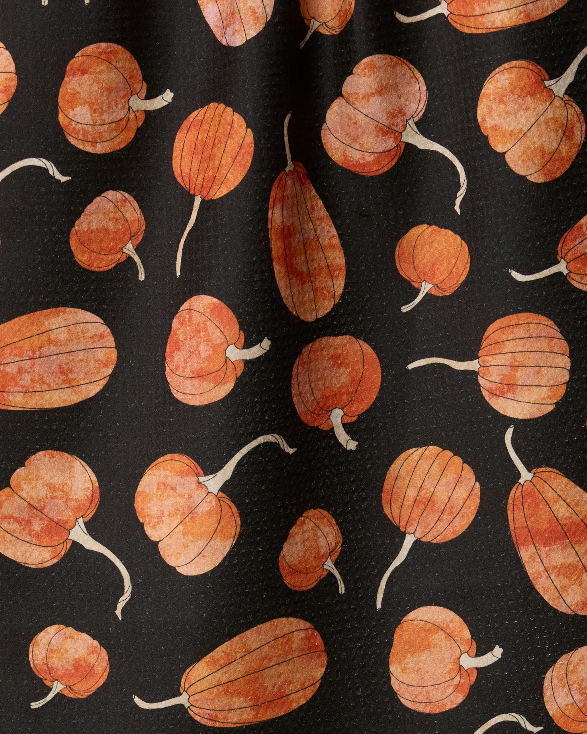 Introducing "Pumpkin Hollow" by Geometry—a festive, autumn-themed kitchen tea towel crafted from recycled materials. This design features a scattering of orange pumpkins in different shapes and sizes, each with a white stem, set against a black background for a charming seasonal touch.
