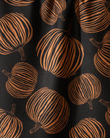 Geometry’s Pumpkin Noir kitchen towel features a recycled black fabric adorned with orange pumpkins, each detailed with vertical stripes and brown stems—a bold, festive design ideal for autumn or Halloween.