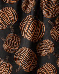 Geometry’s Pumpkin Noir kitchen towel features a recycled black fabric adorned with orange pumpkins, each detailed with vertical stripes and brown stems—a bold, festive design ideal for autumn or Halloween.