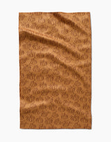 Aubrey Fairchilds Pumpkin Patchwork tea towel features a brown background with an all-over pattern of darker brown, outlined pumpkins, shown flat with subtle wrinkles.