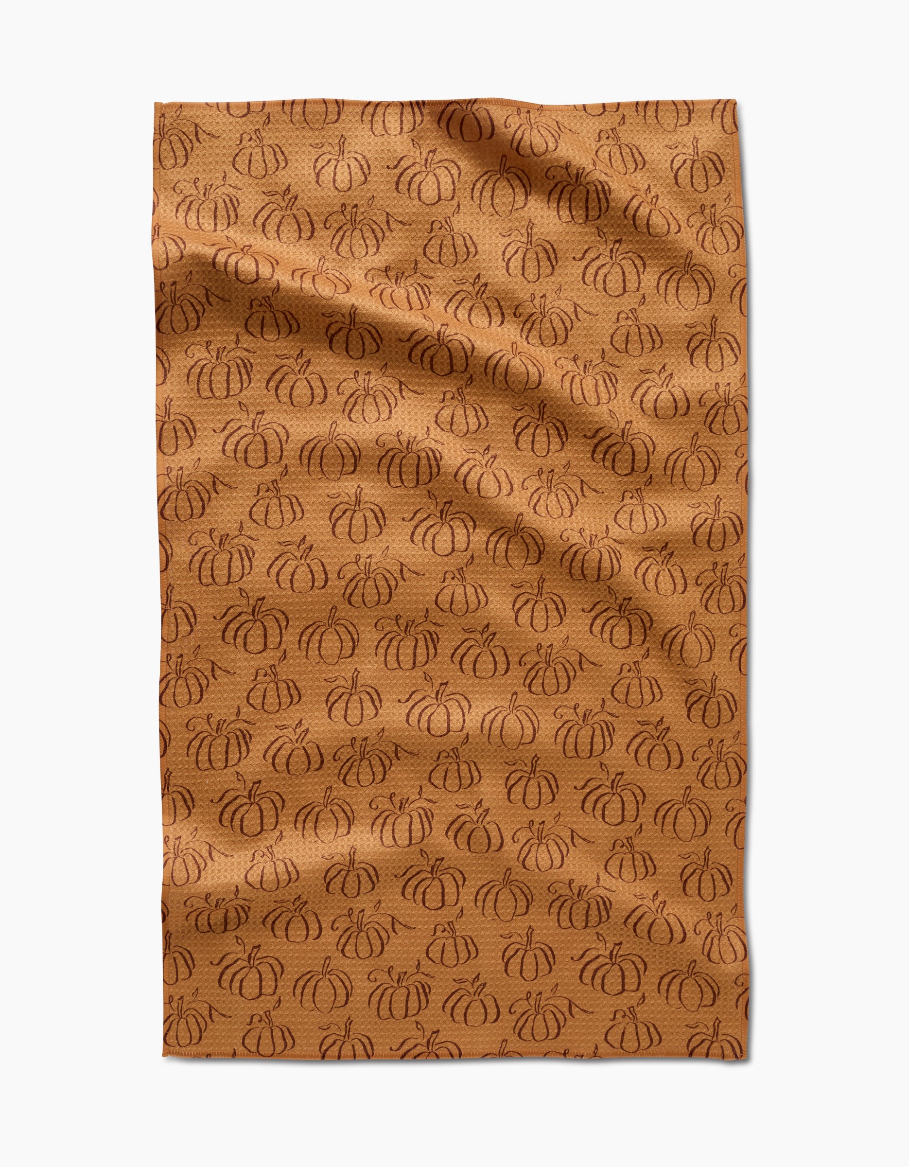 Aubrey Fairchilds Pumpkin Patchwork tea towel features a brown background with an all-over pattern of darker brown, outlined pumpkins, shown flat with subtle wrinkles.