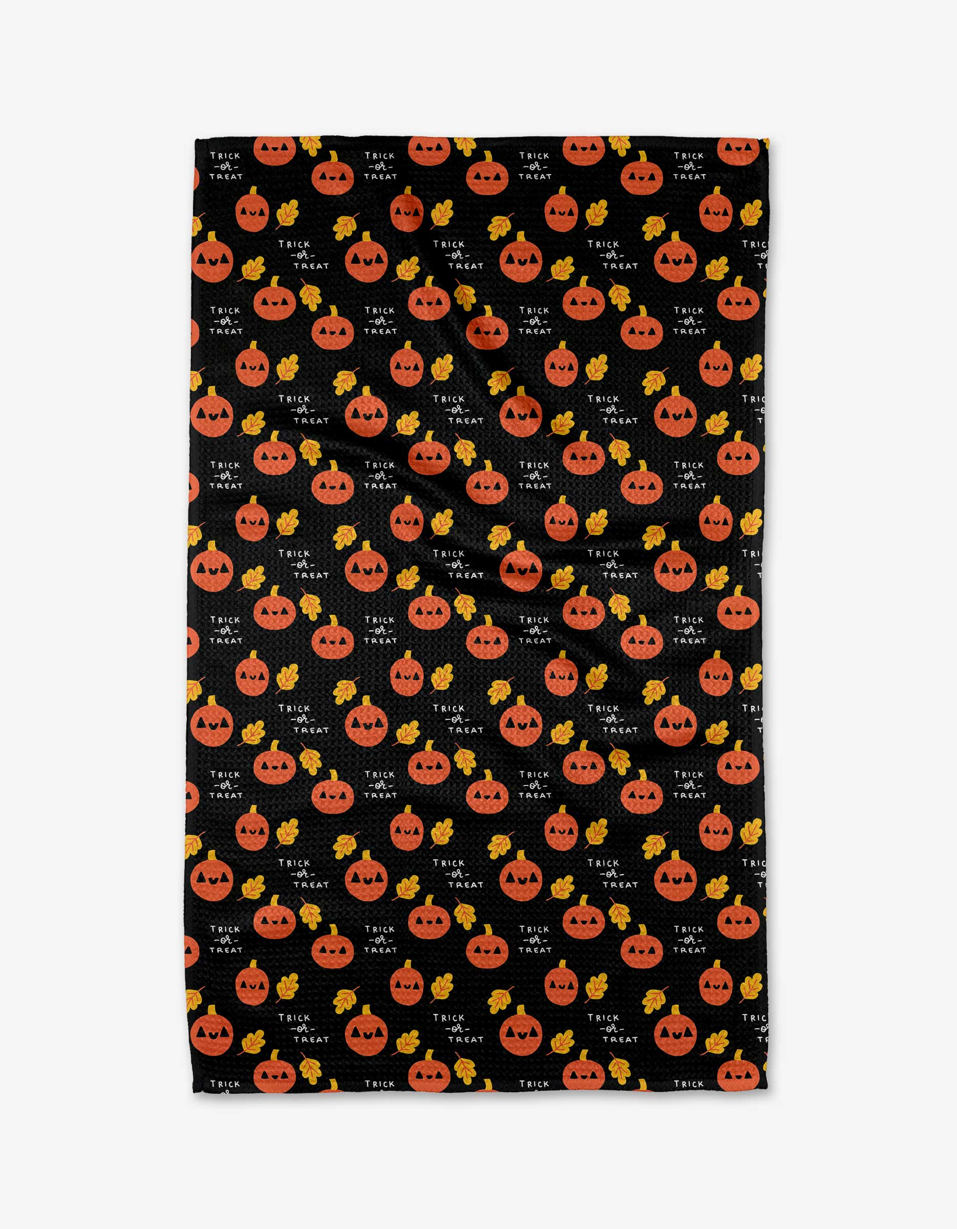 The Pumpkins kitchen towel by Genna Blackburn is rectangular, black, made from recycled materials, and features a repeating pattern of smiling orange jack-o-lanterns, yellow candies, and Trick or Treat in white.