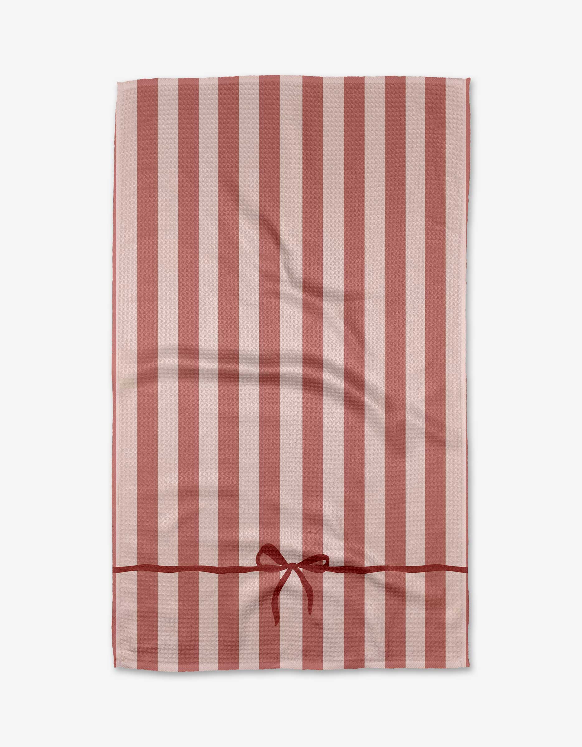 The Kelsi Fullmer Put A Bow On It tea towel features pink and white stripes, a red bottom stripe, and a decorative bow center. Made from ultra-absorbent Geoweave fabric, it’s shown flat on a white background.
