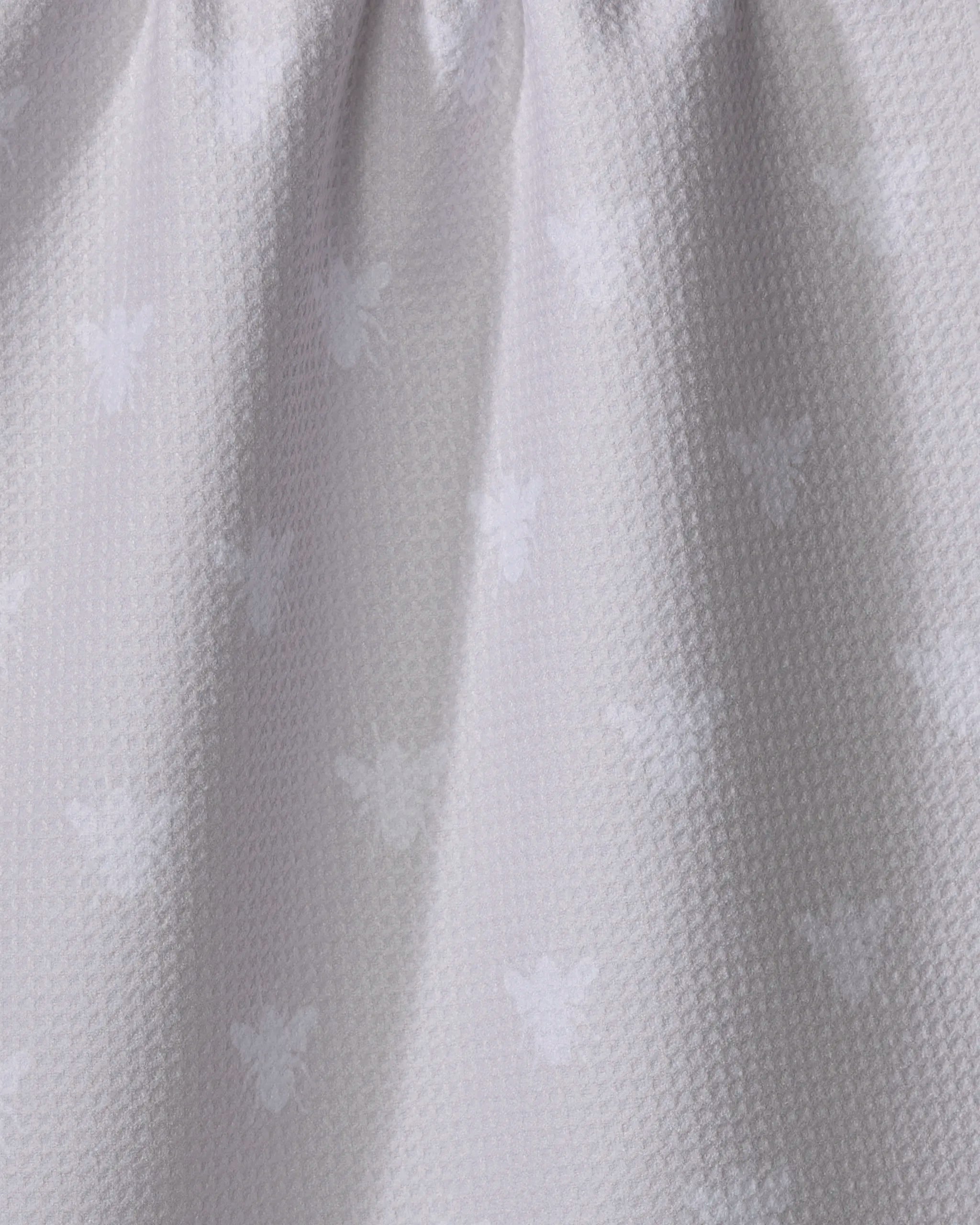 Close-up of The Buy Guide’s Queen Bee - Beige kitchen towel made from recycled materials, showcasing a subtle bee pattern on soft, gently folded fabric with a slightly raised weave.