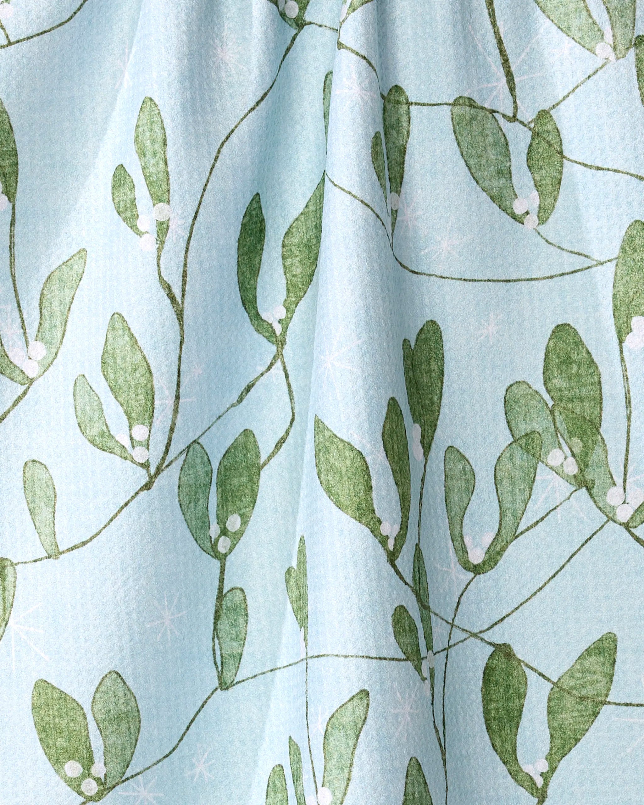 The Quiet Morning tea towel by Pascale Dilger features a light blue hue with green leafy branches and white berry motifs, evoking mistletoe. Made from recycled materials, the fabric offers a subtly textured look and soft folds.