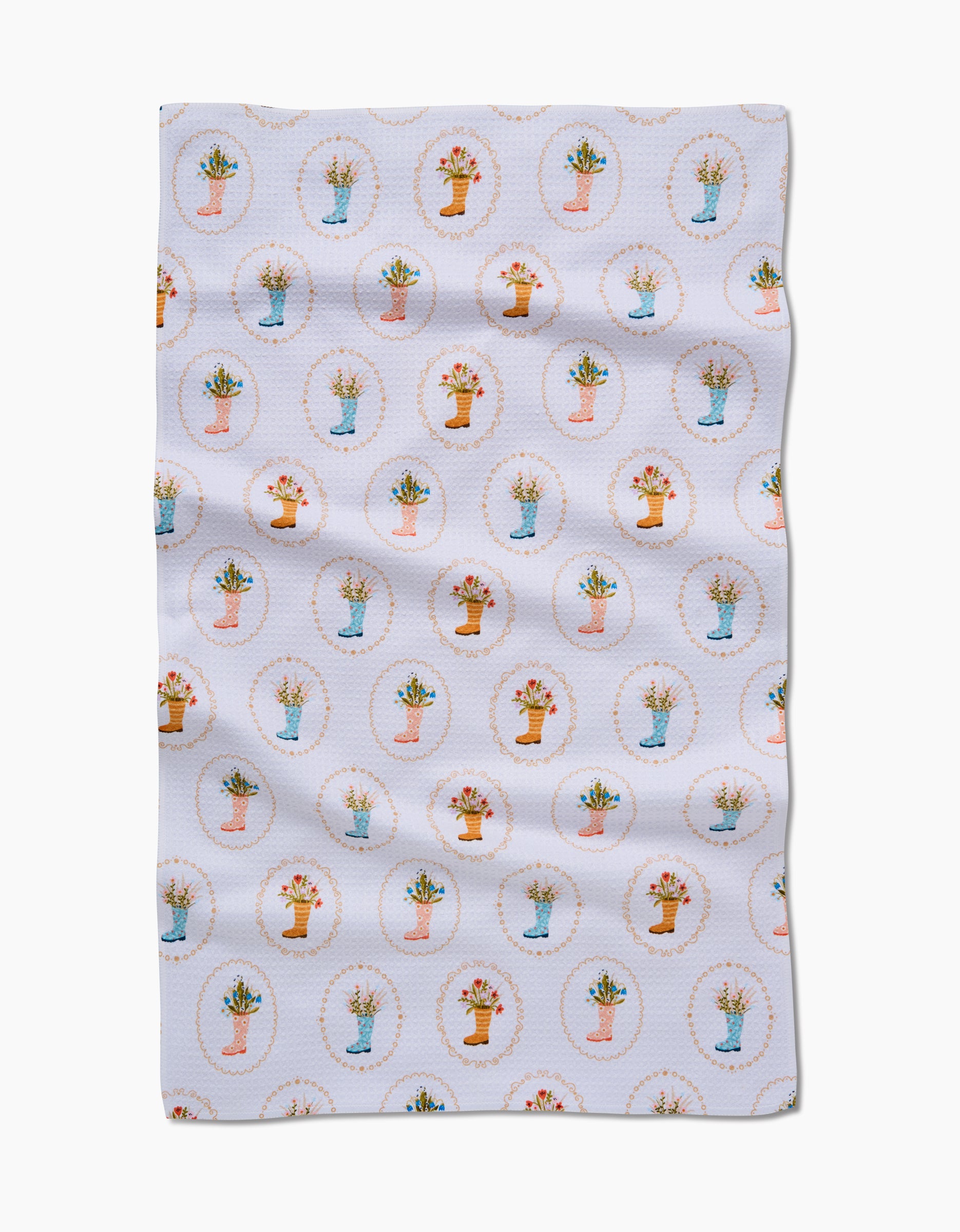The Sara Mari Rainboots in Bloom tea towel features a white background with a repeating pattern of small potted plants and flowers in dotted circles, crafted from soft Geoweave fabric and gently wrinkled.
