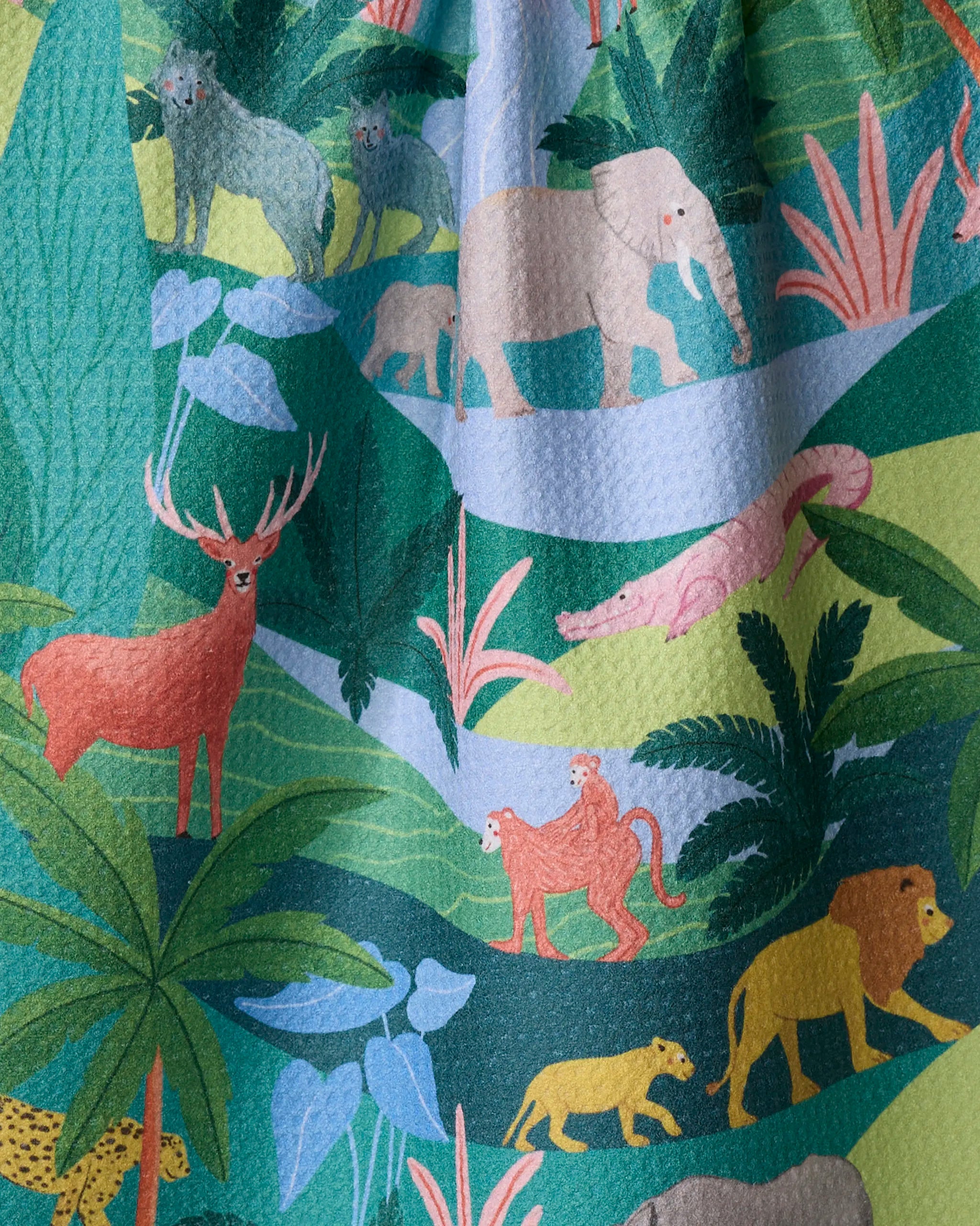 “Rain Forest” by Ceyda Alasar: an ultra-absorbent towel made from recycled materials, featuring illustrations of elephants, a stag, monkeys, a lion, a leopard, and a crocodile amid lush tropical plants and rivers.