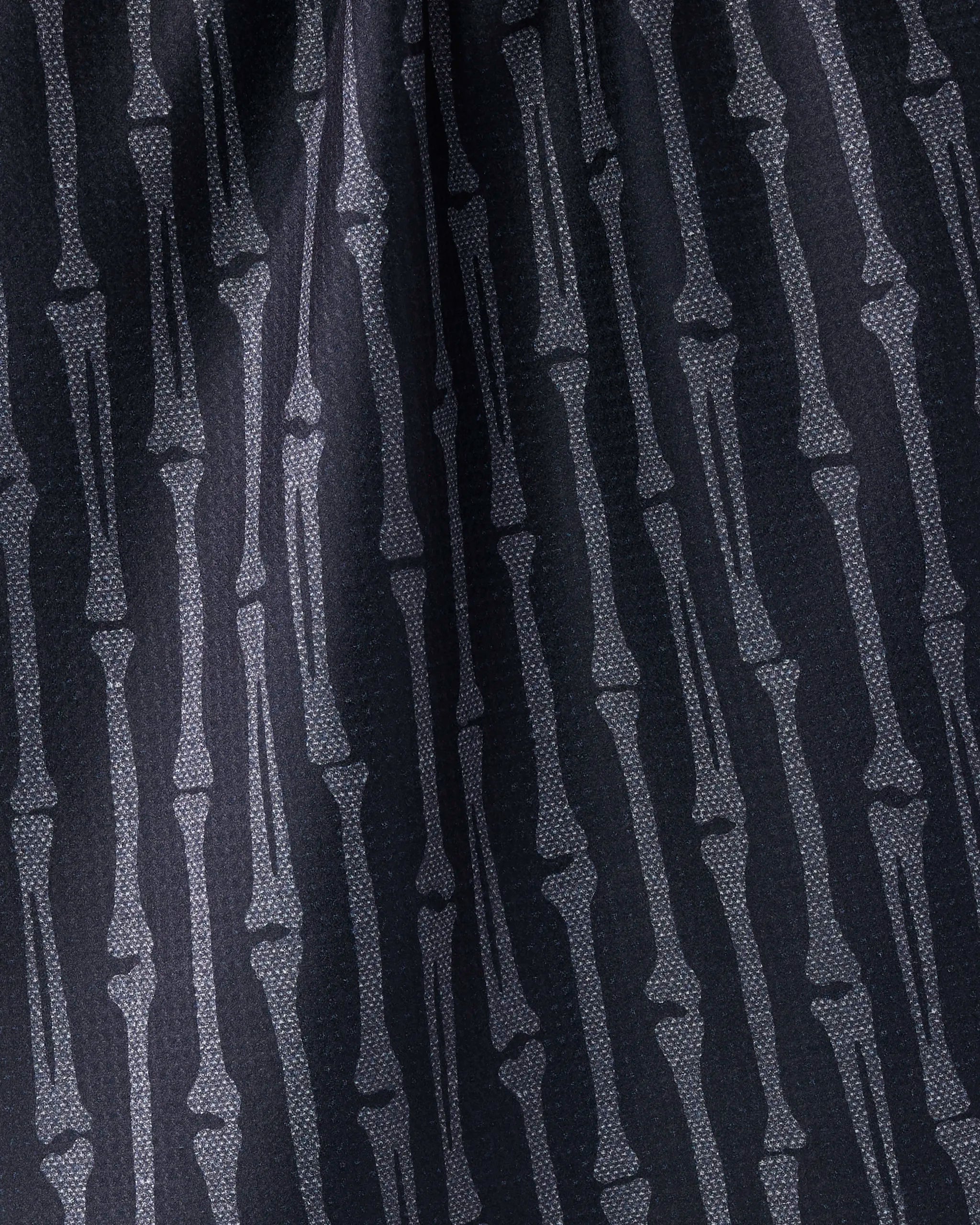 Close-up of the Geometry "Rattler" tea towel, ultra-absorbent and eco-friendly, featuring a repeating white bone silhouette pattern on a dark background for a bold, skeletal look. Crafted from recycled materials.