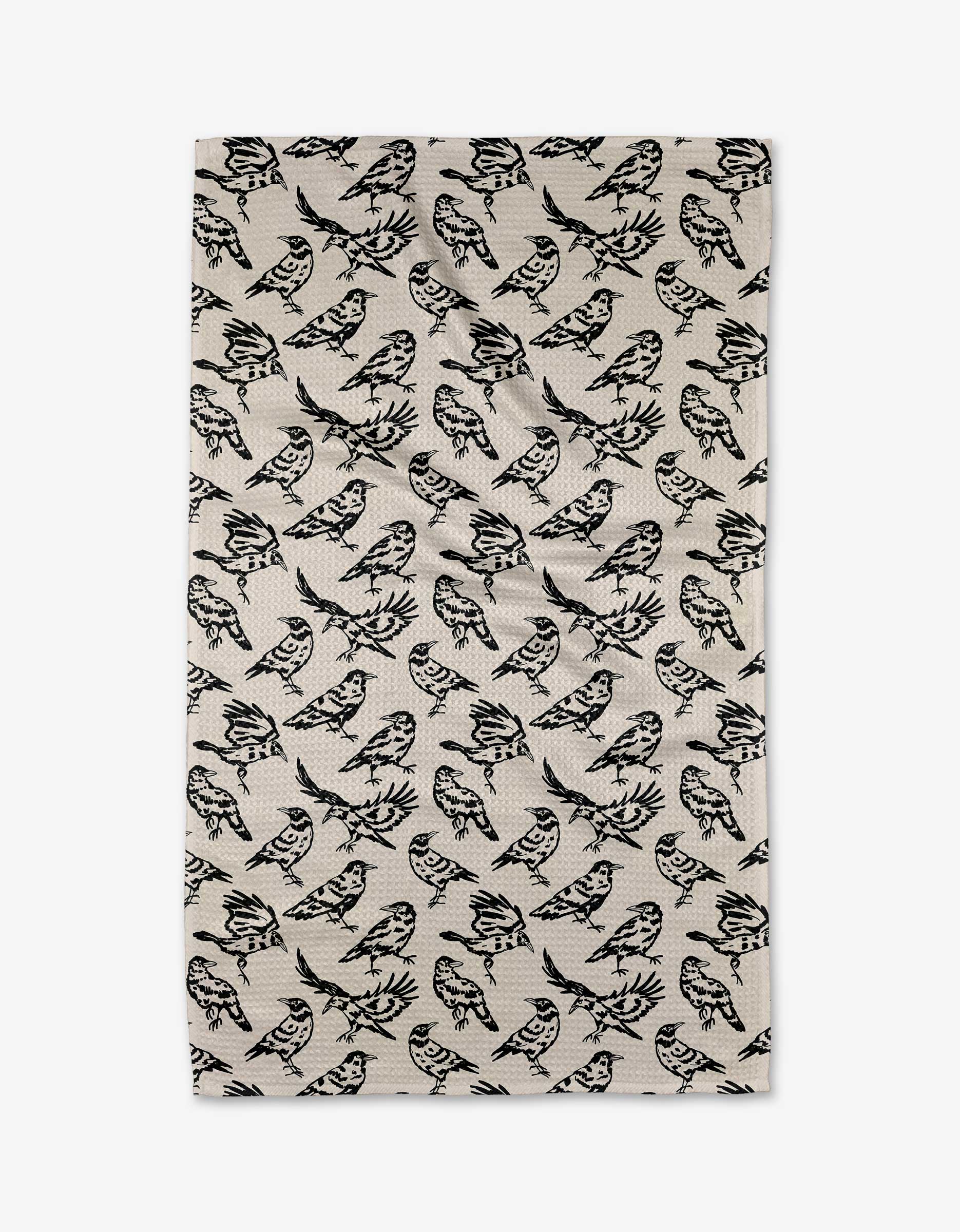 The Raven tea towel by Kayla Ann features a beige and white background with a repeating pattern of black illustrated birds in various directions. This quick-drying towel is ideal for any modern kitchen.