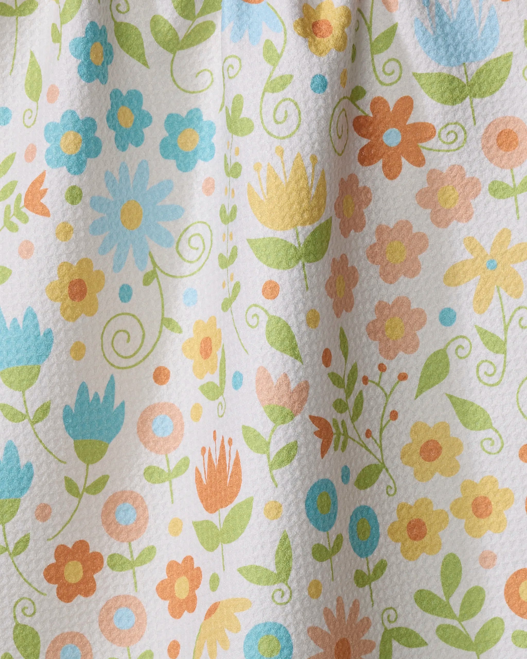 The Remindful Rememberings tea towel by Mindfulnice features a bright floral pattern with blue, yellow, orange, and pink flowers, green leaves, and swirling stems on textured white—evoking a cheerful spring or summer vibe.