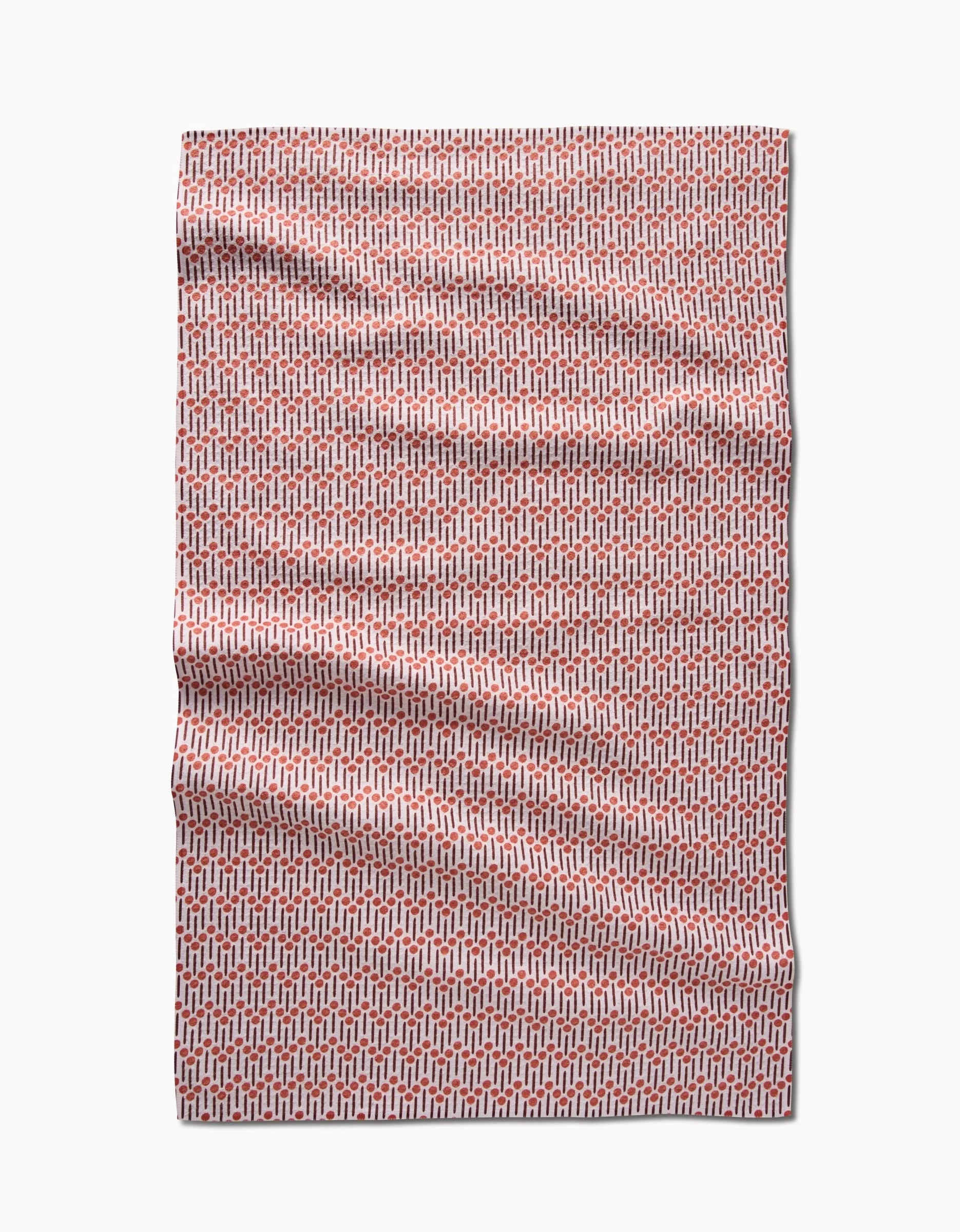 The Retro Geo tea towel by Teri the Butter features a red and white geometric pattern of small interlocking shapes. Made from recycled materials, its shown laid flat with light wrinkles on a plain white background.