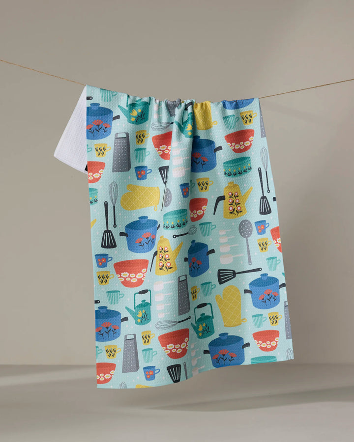 The Retro Kitchen tea towel by Megan Kampa is made from recycled materials and features playful images of pots, bowls, and utensils in vibrant red, blue, yellow, and teal hues.