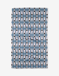 The Anette Heiberg Retro Rain tea towel displays a repeating geometric pattern of blue diamonds and white teardrops with black dots, arranged in vertical rows on a white background.