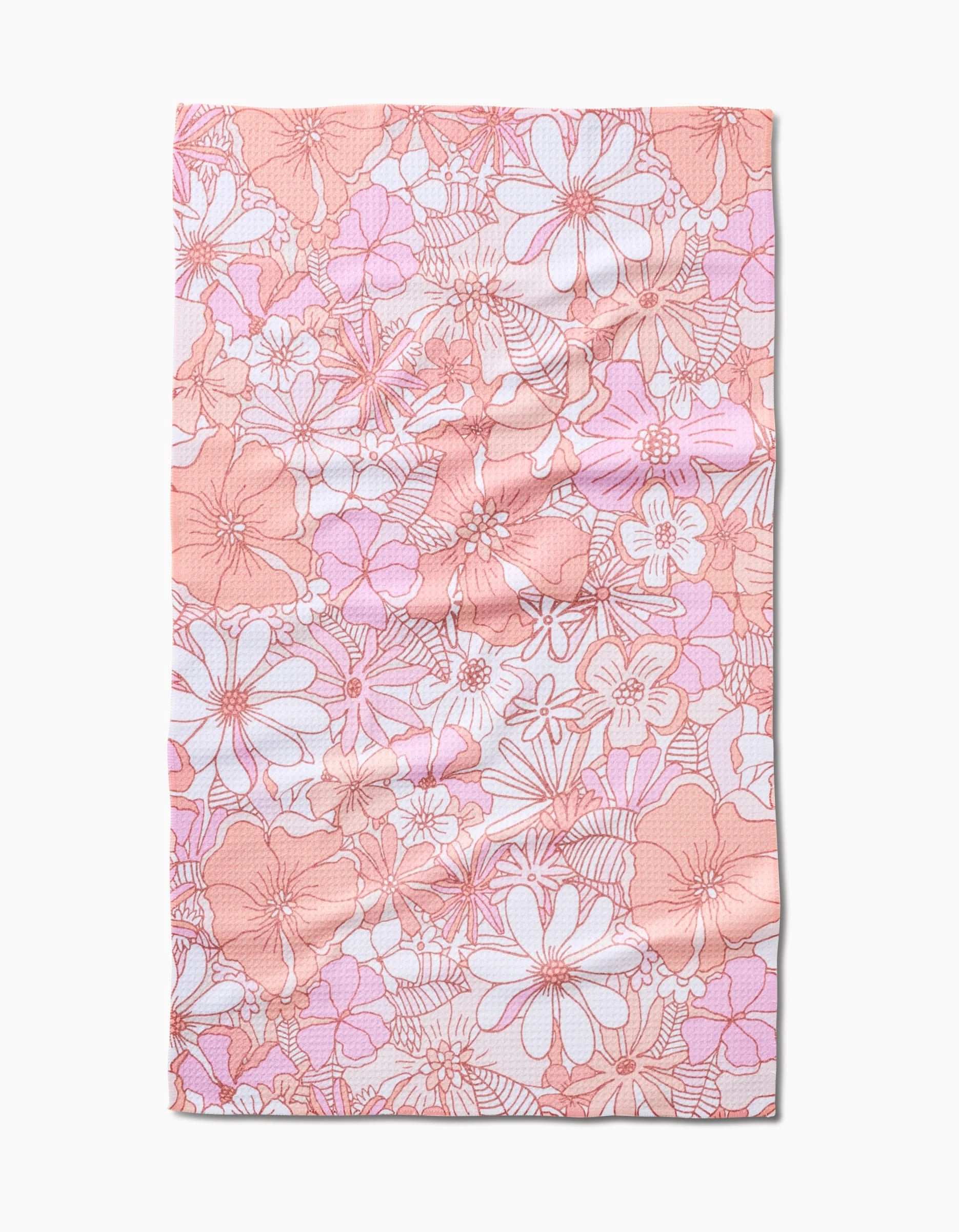 The Retro Vibes tea towel by Marina Solodka is a rectangular, crinkled-texture towel made from recycled materials, featuring a pink and white floral pattern on a light background.
