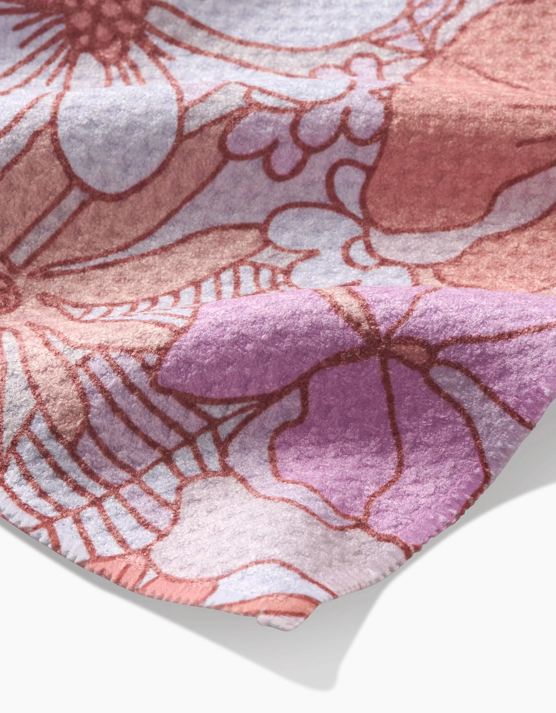 A close-up of the Retro Vibes Tea Towel by Marina Solodka, crafted from soft Geoweave fabric and featuring a pink, purple, and mauve floral pattern with detailed texture and curved edges.