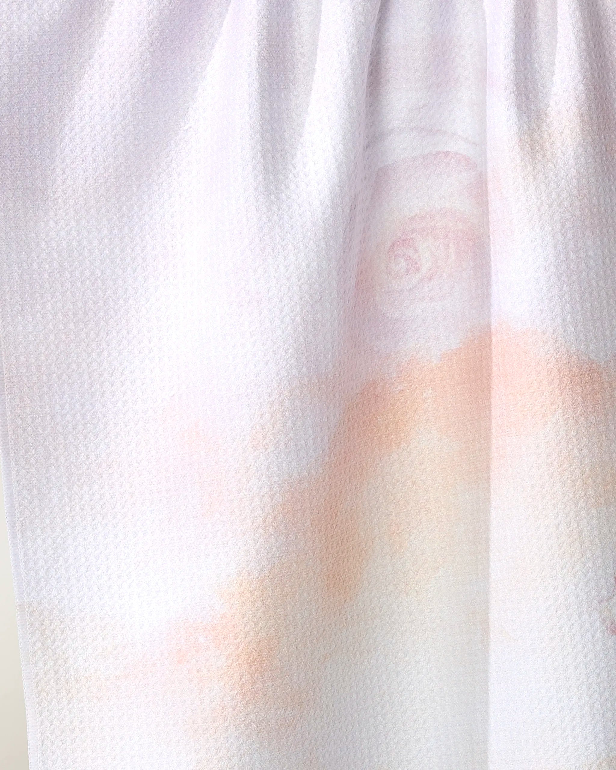 A close-up of the Stefanie Bales Rhapsody in Bloom tea towel, featuring soft, recycled white fabric with pastel pink and peach floral patterns and a subtle rose design. Lightly gathered at the top for an elegant look.
