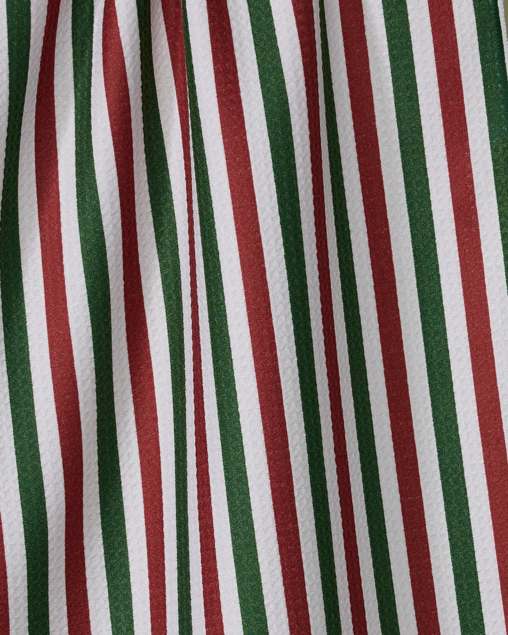 Close-up of the Ribbon Green Red tea towel by Geometry, featuring vertical red, green, and white stripes for a festive look. Made from quick-drying recycled materials, the textured fabric displays visible folds.
