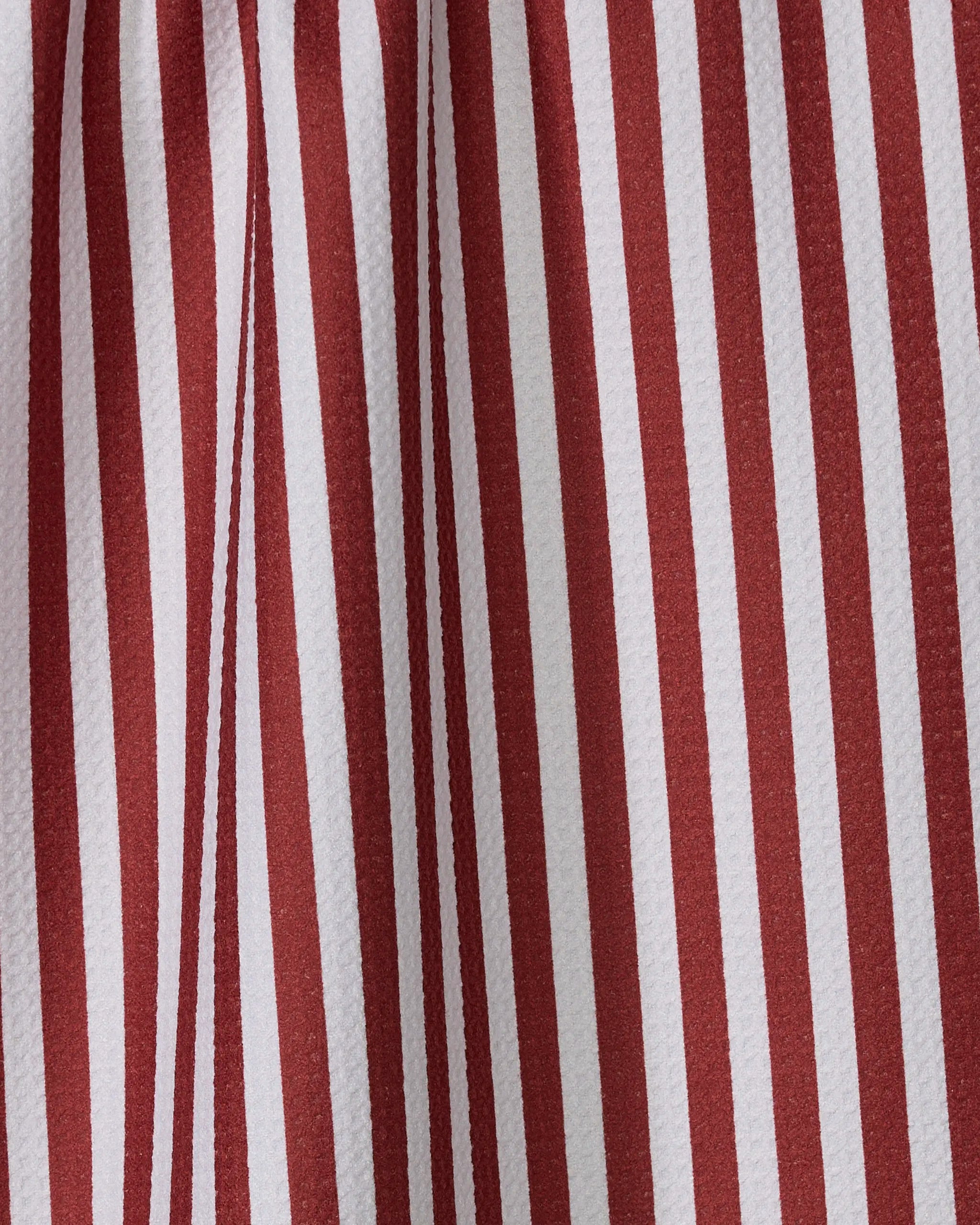 Close-up of Geometry's Ribbon Red tea towel, made from recycled materials and featuring vertical red and white stripes. Soft fabric folds enhance the striped pattern with shadows and depth.