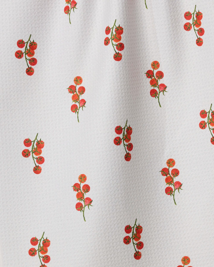Geometry’s "Ripe and Ready Scattered" is a white recycled kitchen towel featuring a textured finish with evenly spaced red cherry tomato vines and green stems across its surface.