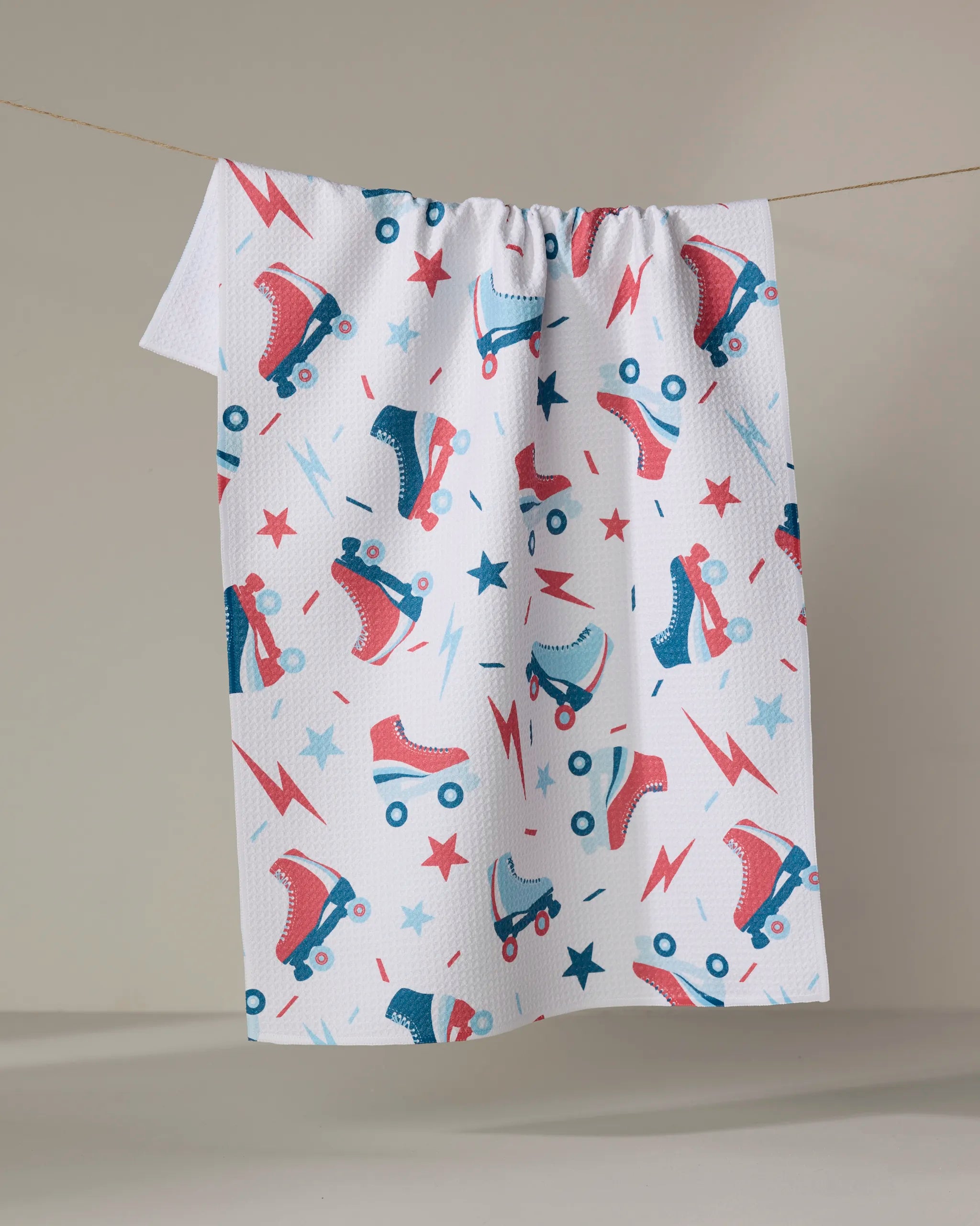 The "Rolling With Stars" tea towel by Hufton Studio features a vibrant pattern of red and blue roller skates, stars, and lightning bolts. Made from recycled materials, it's both eco-friendly and stylish—perfect for brightening any kitchen.