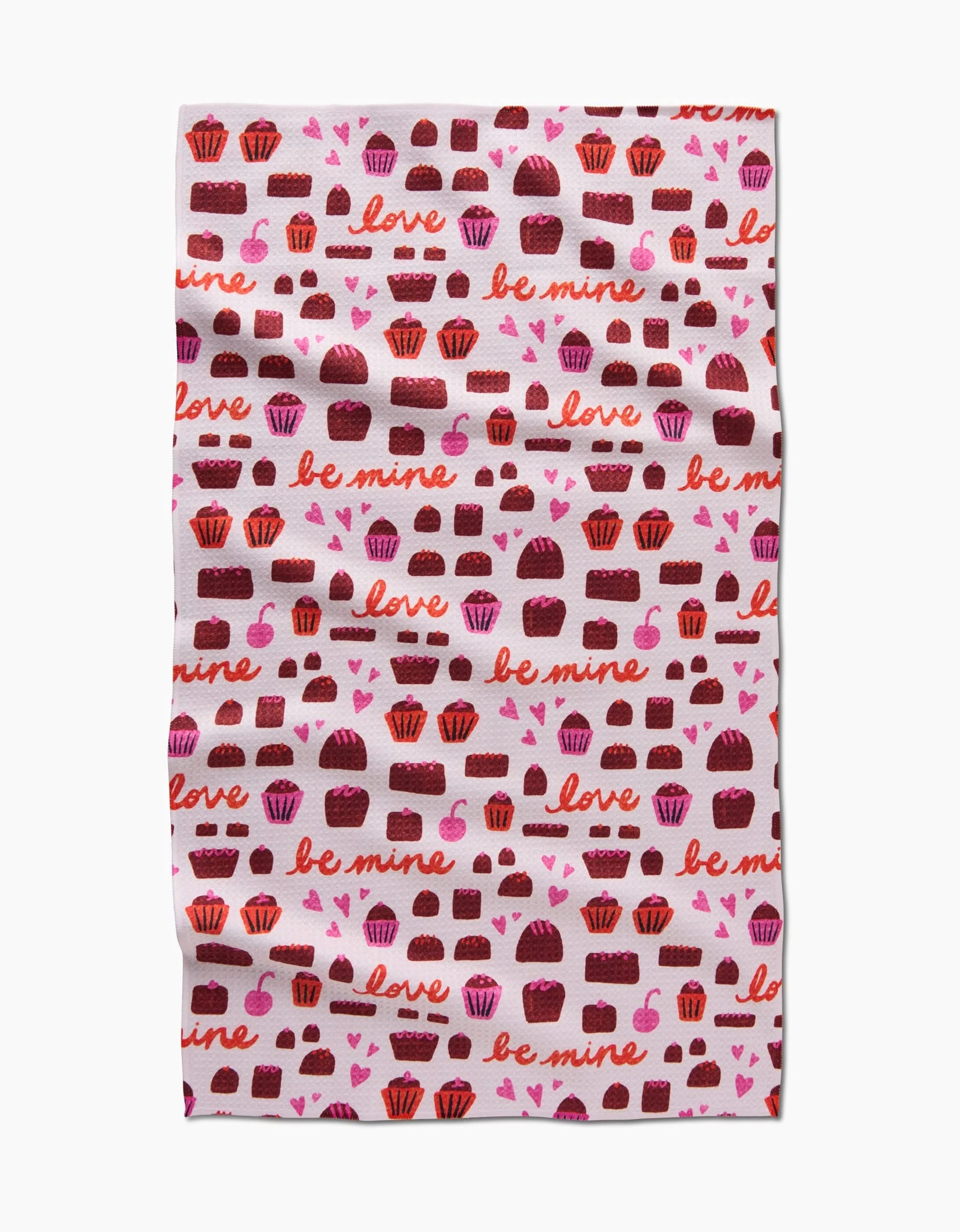 The Romeo tea towel by Amy MacCready features a quick-drying design with pink and brown chocolates, hearts, and words like love and be mine in red and pink on a crisp white background.