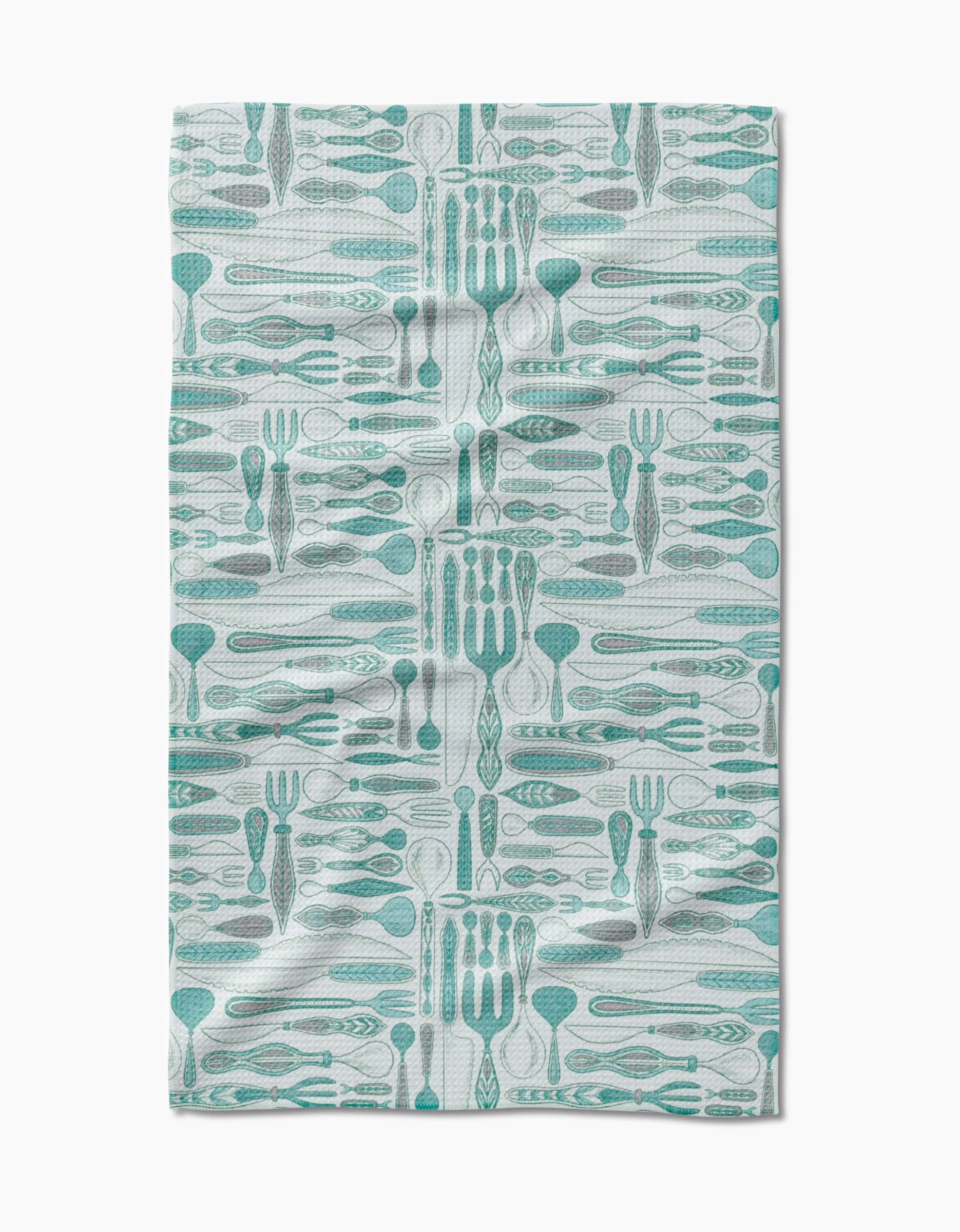 The Romy kitchen towel by Amy MacCready features a teal and gray utensil pattern on white Geoweave fabric. Ultra-absorbent, eco-friendly, and stylish, it boasts a slightly wrinkled finish for added charm.