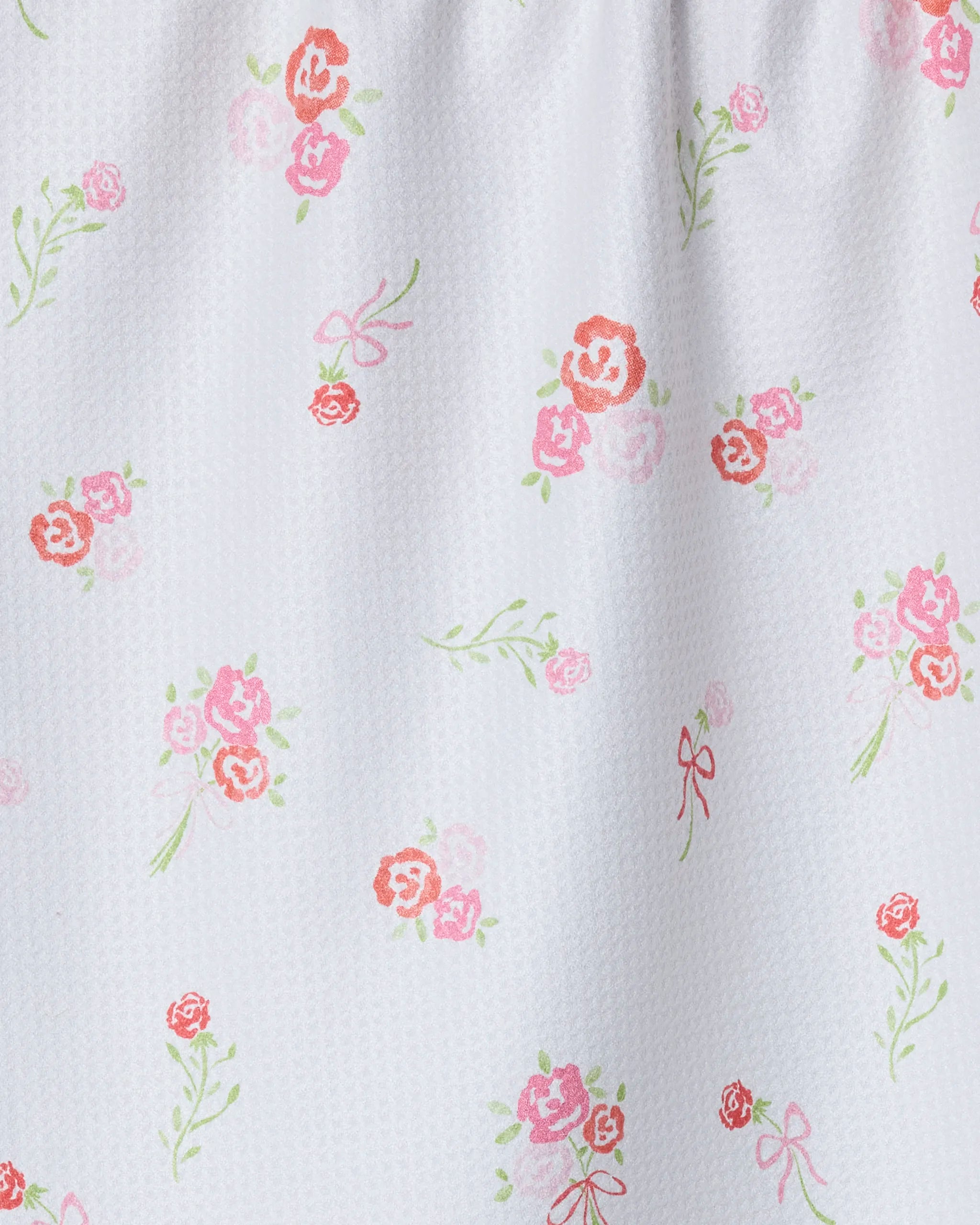 The Geometry Rosy Cheeks tea towel features ultra-absorbent white fabric adorned with small pink and red roses, green leaves, and pink bows, plus a subtle textured look—perfect for everyday kitchen use.