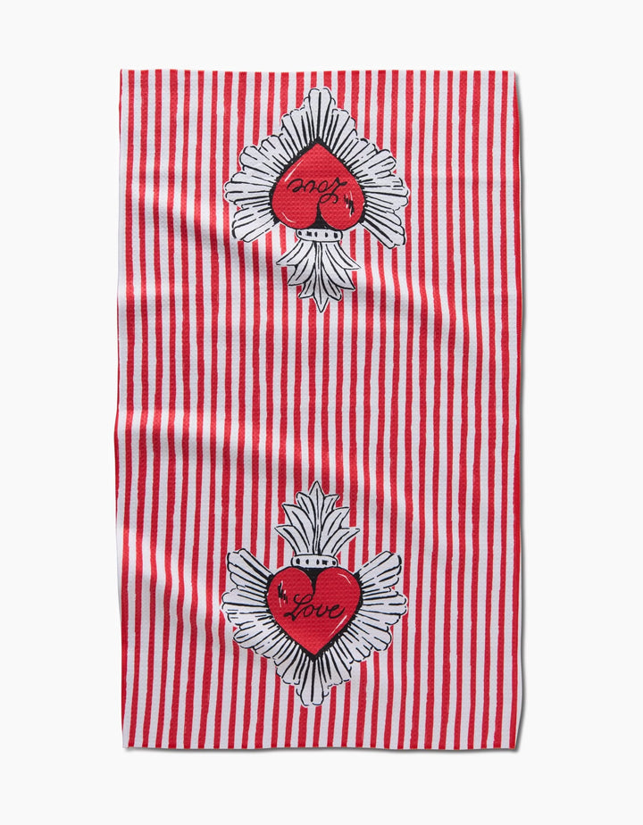 The Sacred Striped Love Hearts tea towel by Hufton Studio features red and white vertical stripes, two embroidered red hearts with “Love” and white wings near the top and bottom, on ultra-absorbent fabric.