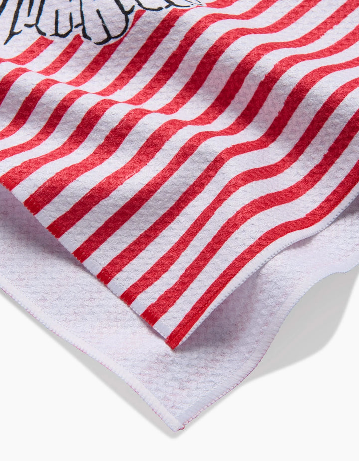 A close-up of the Hufton Studio Sacred Striped Love Hearts tea towel, showing its red and white wavy stripes, part of a black and white illustrated edge design, and textured ultra-absorbent fabric softly folded.