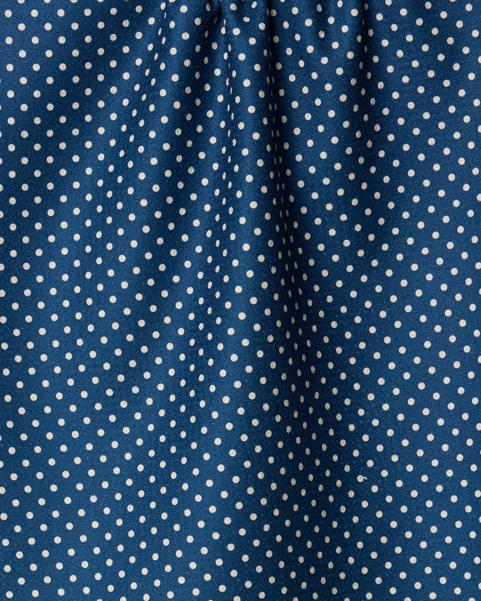 Close-up of Saddle Indigo tea towel by Geometry shows blue fabric with small white diagonal polka dots. Made from recycled materials, the towel displays gentle folds and subtle shadows for added texture.