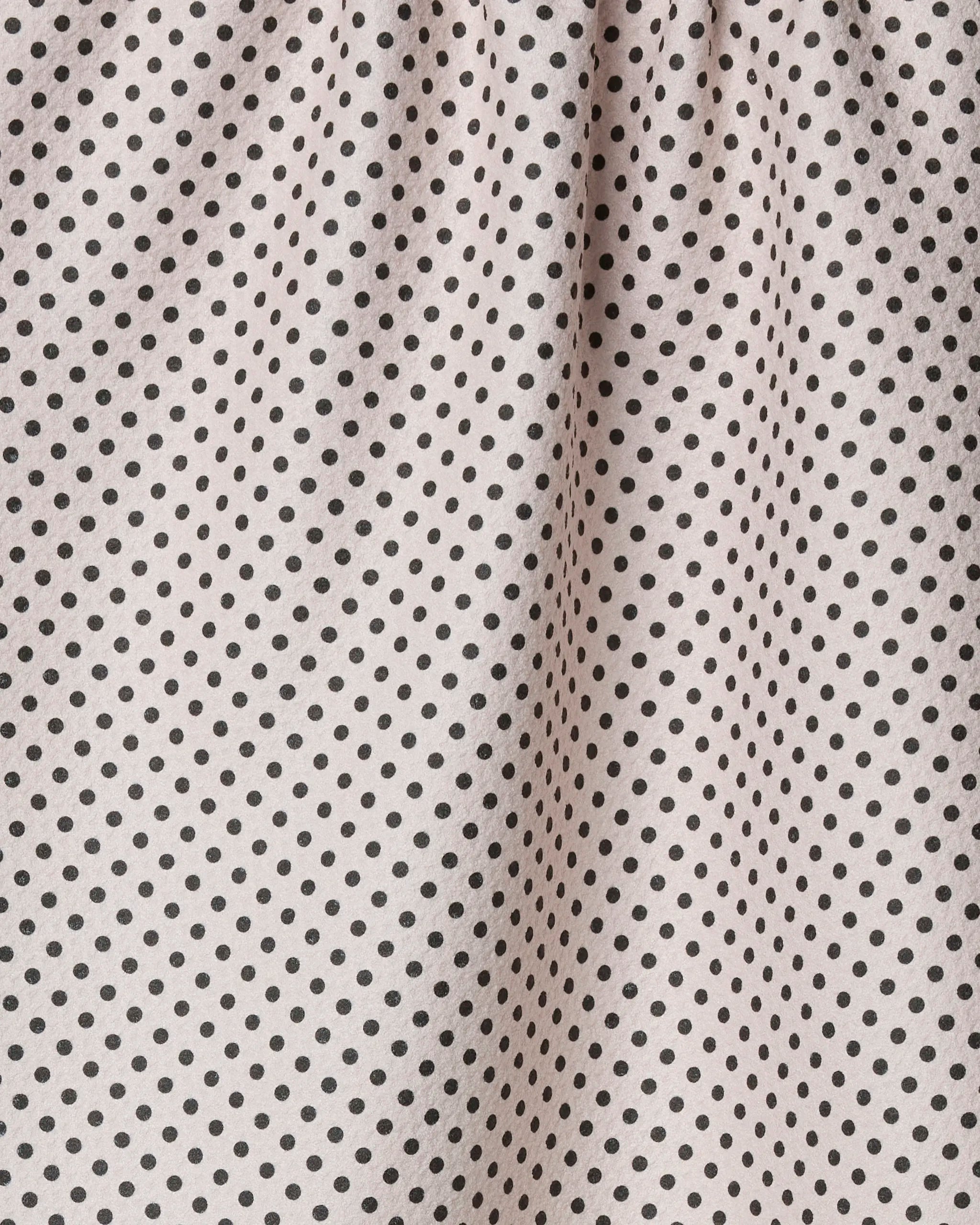 Close-up of Geometry’s Saddle Off White recycled kitchen towel, featuring evenly spaced small black polka dots and gathered top that creates soft vertical folds.