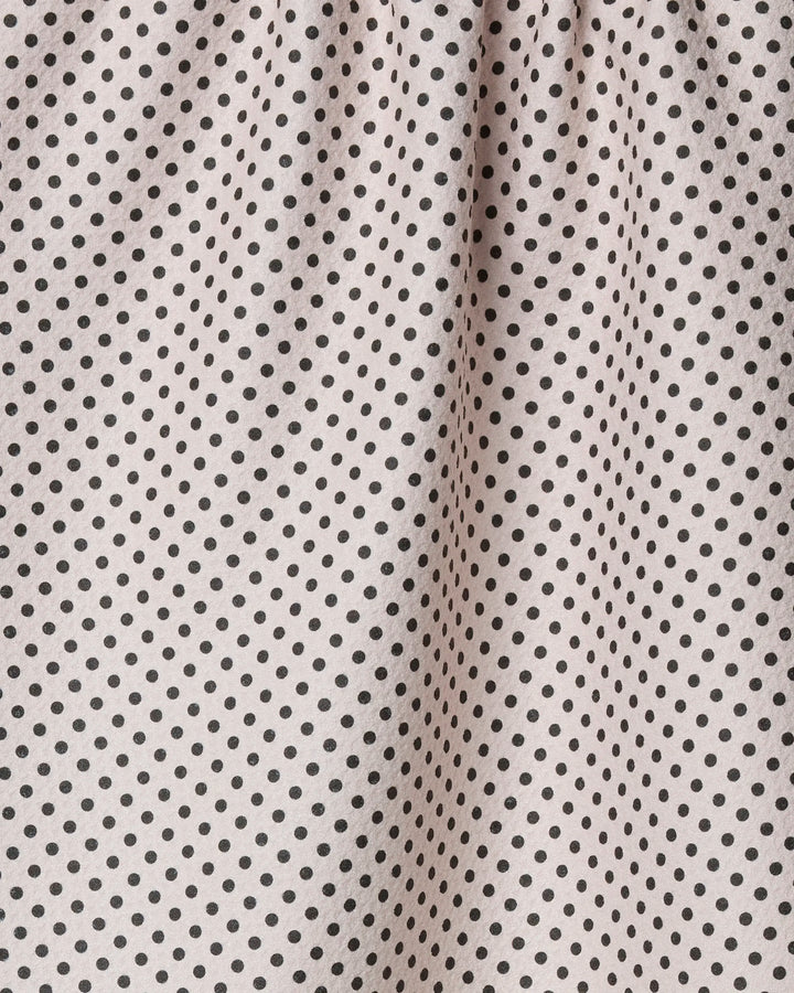 Close-up of Geometry’s Saddle Off White recycled kitchen towel, featuring evenly spaced small black polka dots and gathered top that creates soft vertical folds.