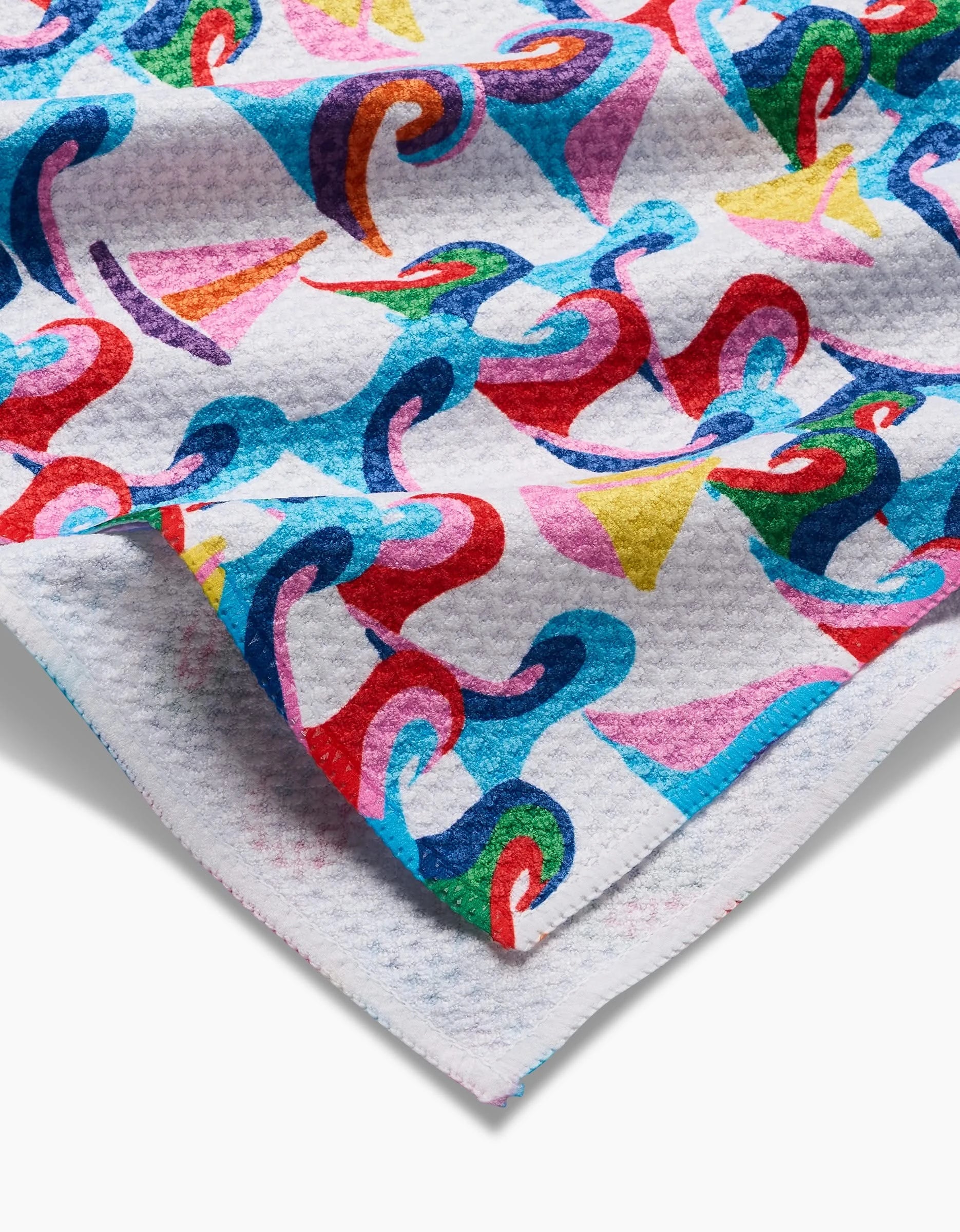 The Sail Safe towel by Ania Zwara Art features vibrant abstract sailboats and waves in red, blue, yellow, green, and pink on white Geoweave fabric. Ultra-absorbent and stylish, its shown partially folded at the corner.