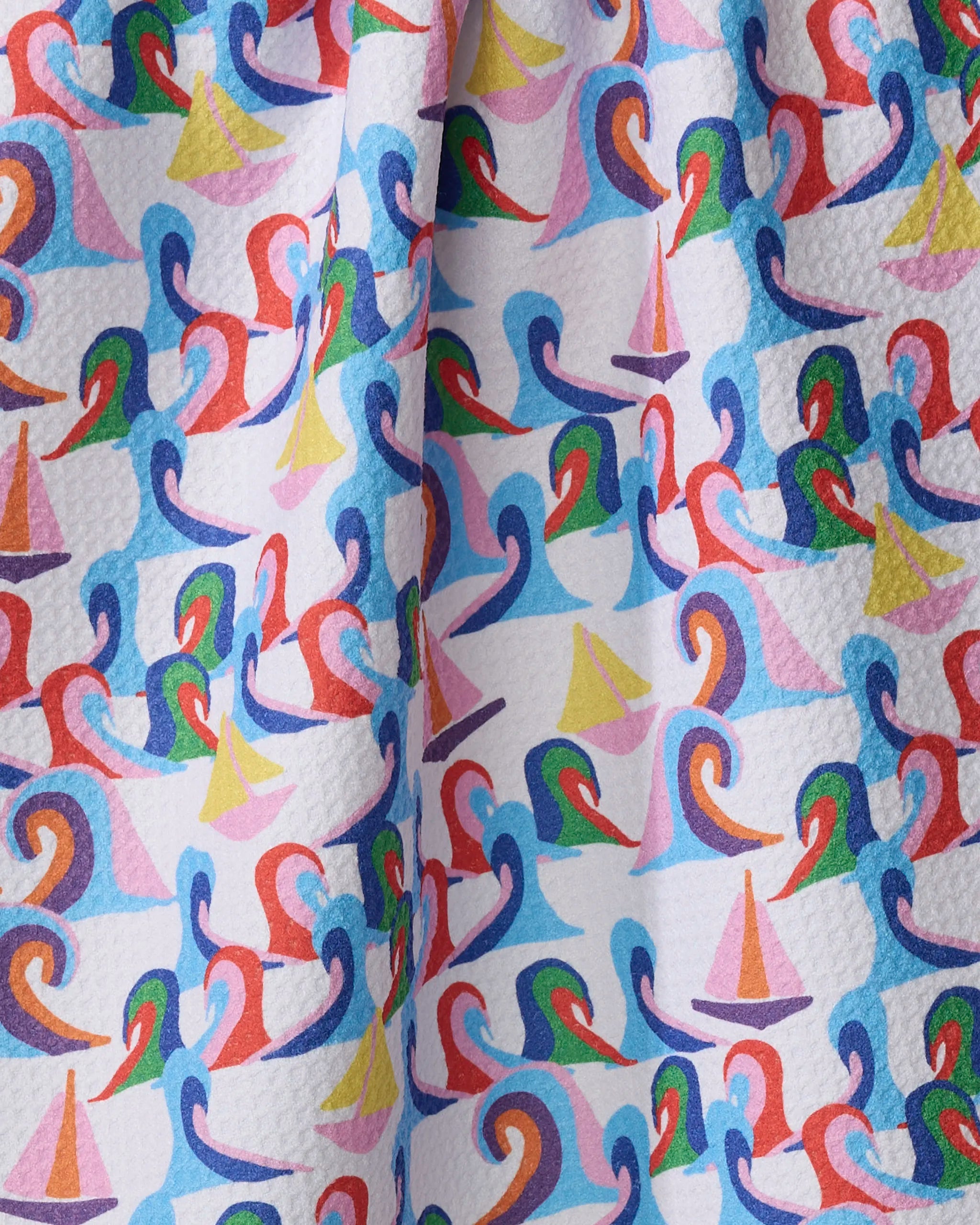 The Sail Safe towel by Ania Zwara Art features colorful swan and sailboat patterns in red, blue, pink, green, and yellow on a white textured background. This quick-drying towel appears slightly gathered or draped.