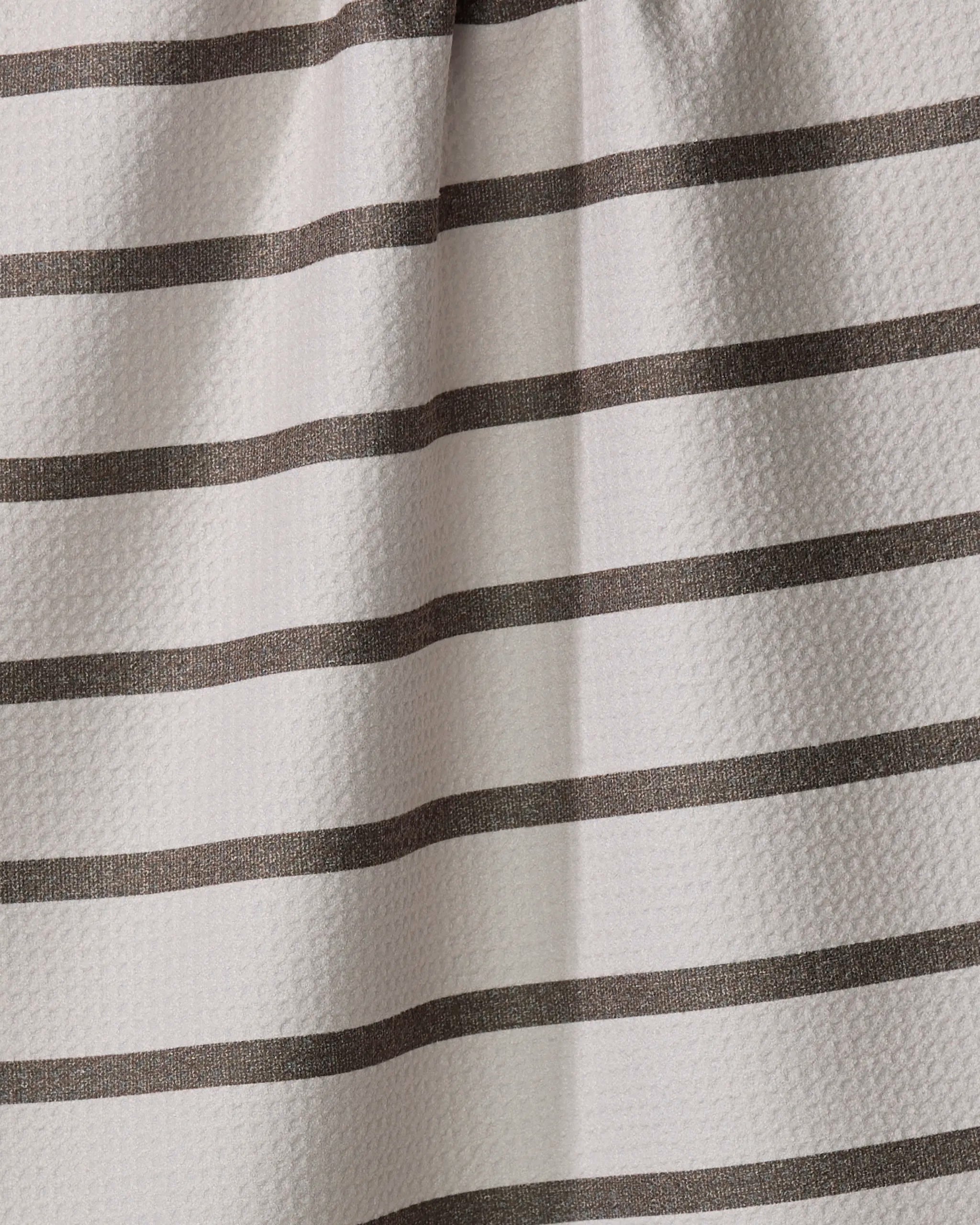 A close-up of the Jenny Keller Salt Air Stripe tea towel shows its textured surface with evenly spaced horizontal dark brown stripes on a light beige background. Made from recycled materials, the fabric has slight folds and subtle shadows.