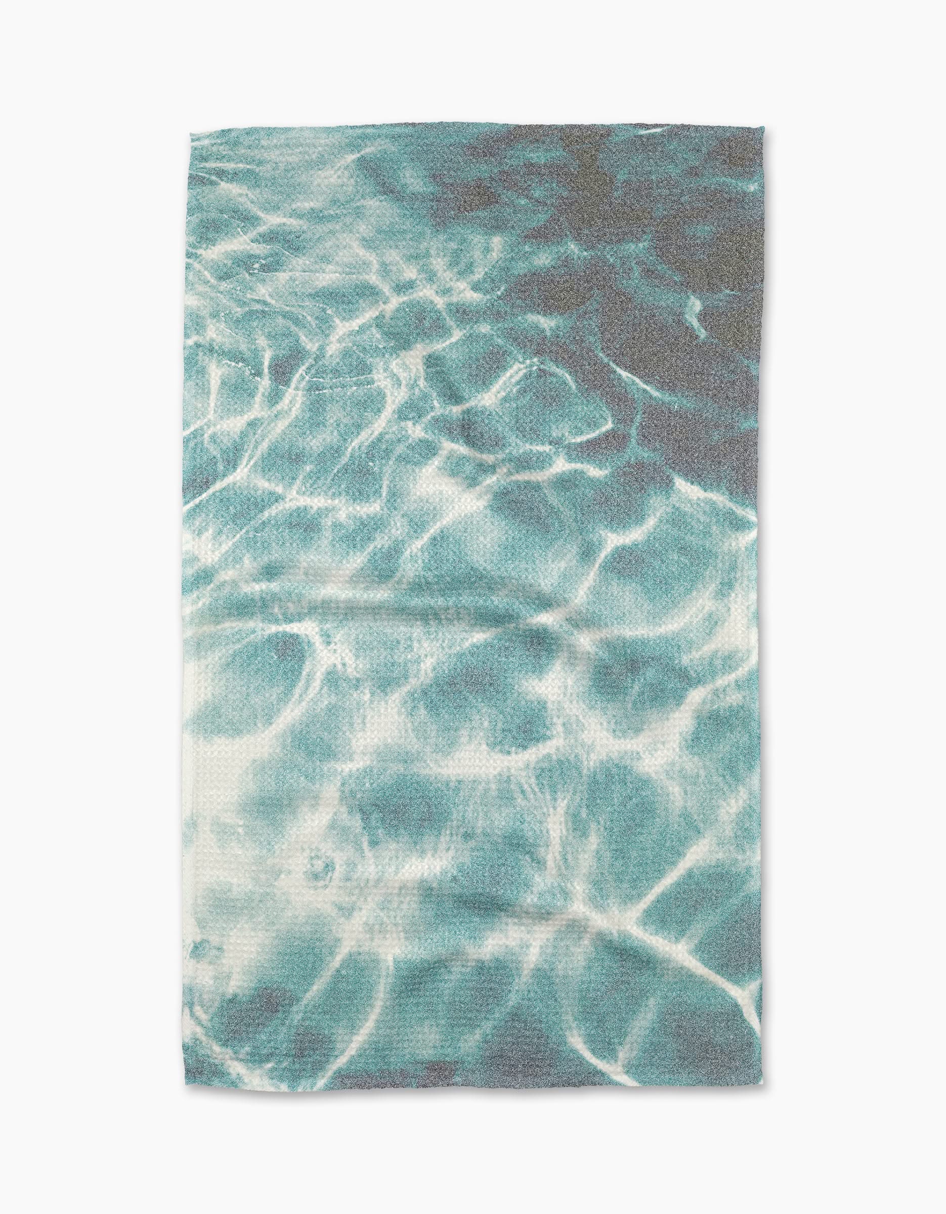 The Geometry Saltwater Glow Tea Towel features a print of sunlight on clear blue water, evoking a swimming pool, and is made from absorbent Geoweave fabric.