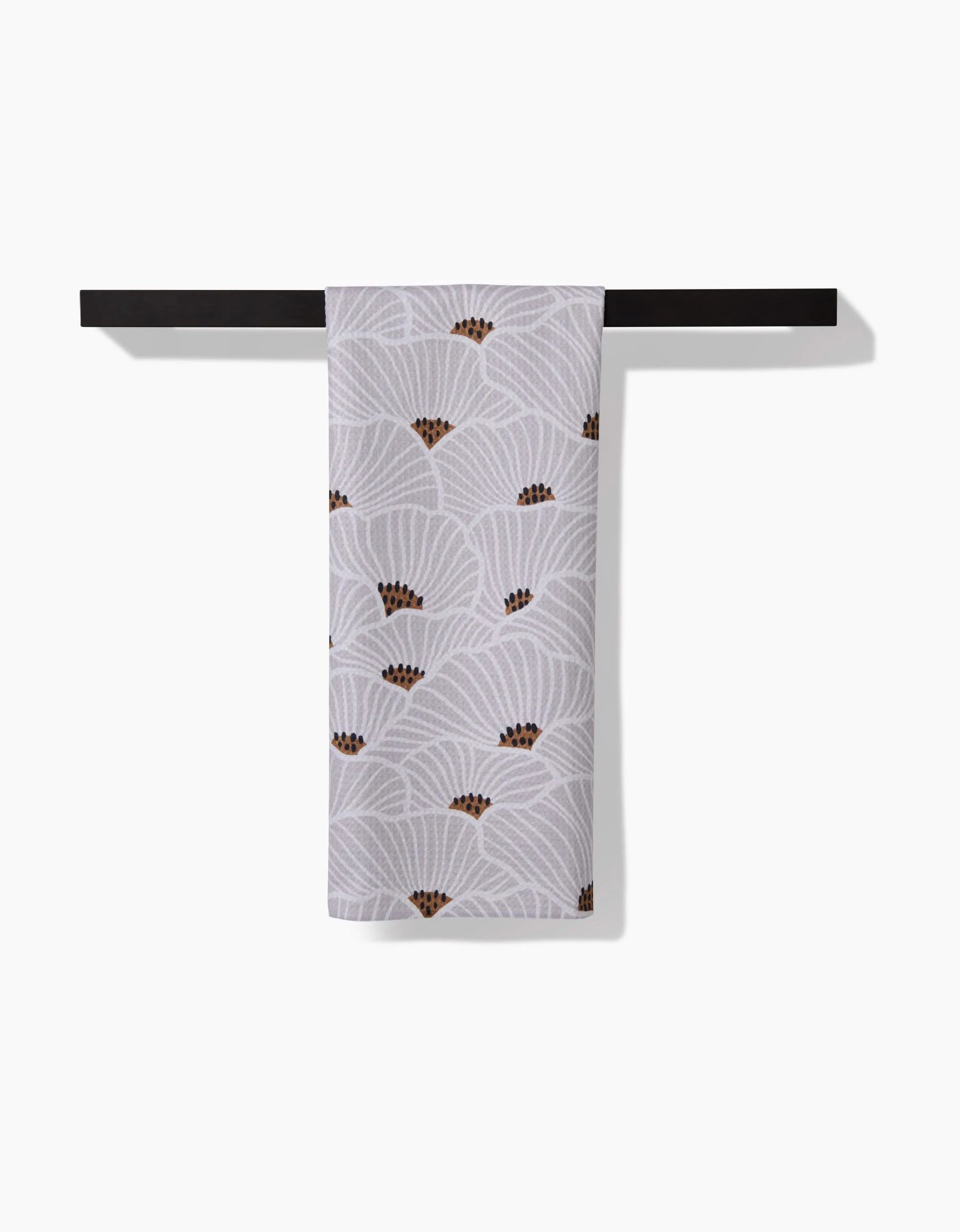 The San Diego tea towel by Amy MacCready, featuring a white base with a repeating fan pattern and brown accents, made from recycled materials, is displayed draped over a black towel bar on a plain white background.