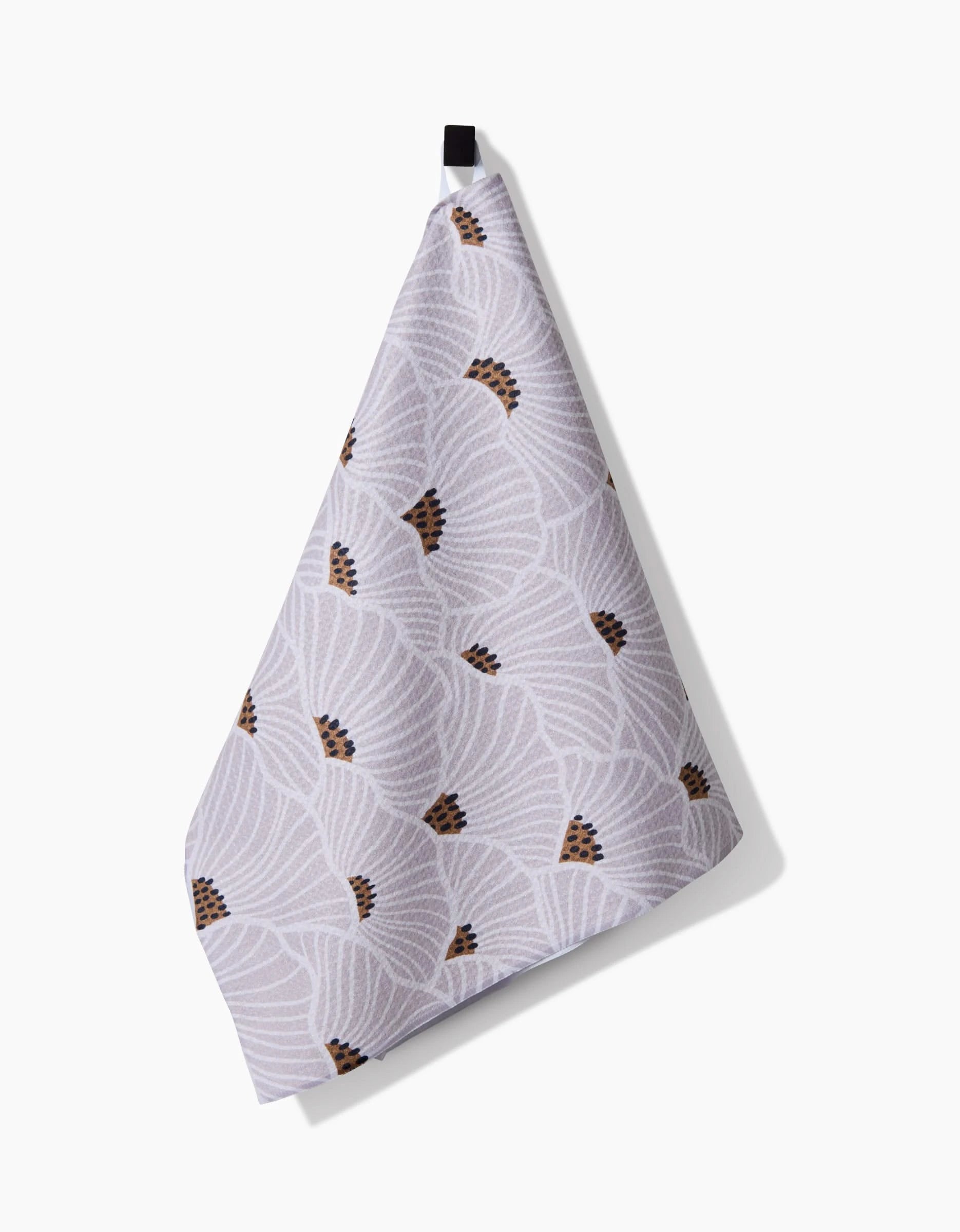 The “San Diego” tea towel by Amy MacCready features Geoweave™ fabric in white with a subtle fan-shaped geometric pattern and small brown accents, shown hanging from a black loop against a plain white background.