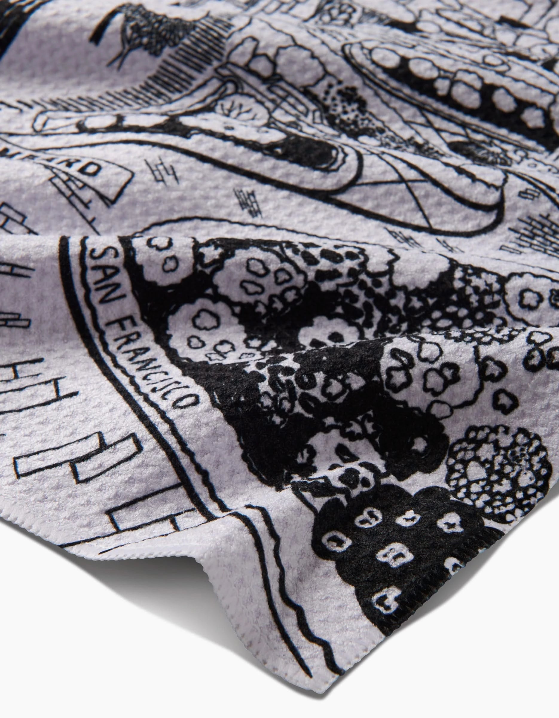 A close-up of the Elisabeth Wing San Francisco tea towel, featuring a black-and-white map-like design with abstract drawings and patterns, all crafted from post-consumer recycled materials.