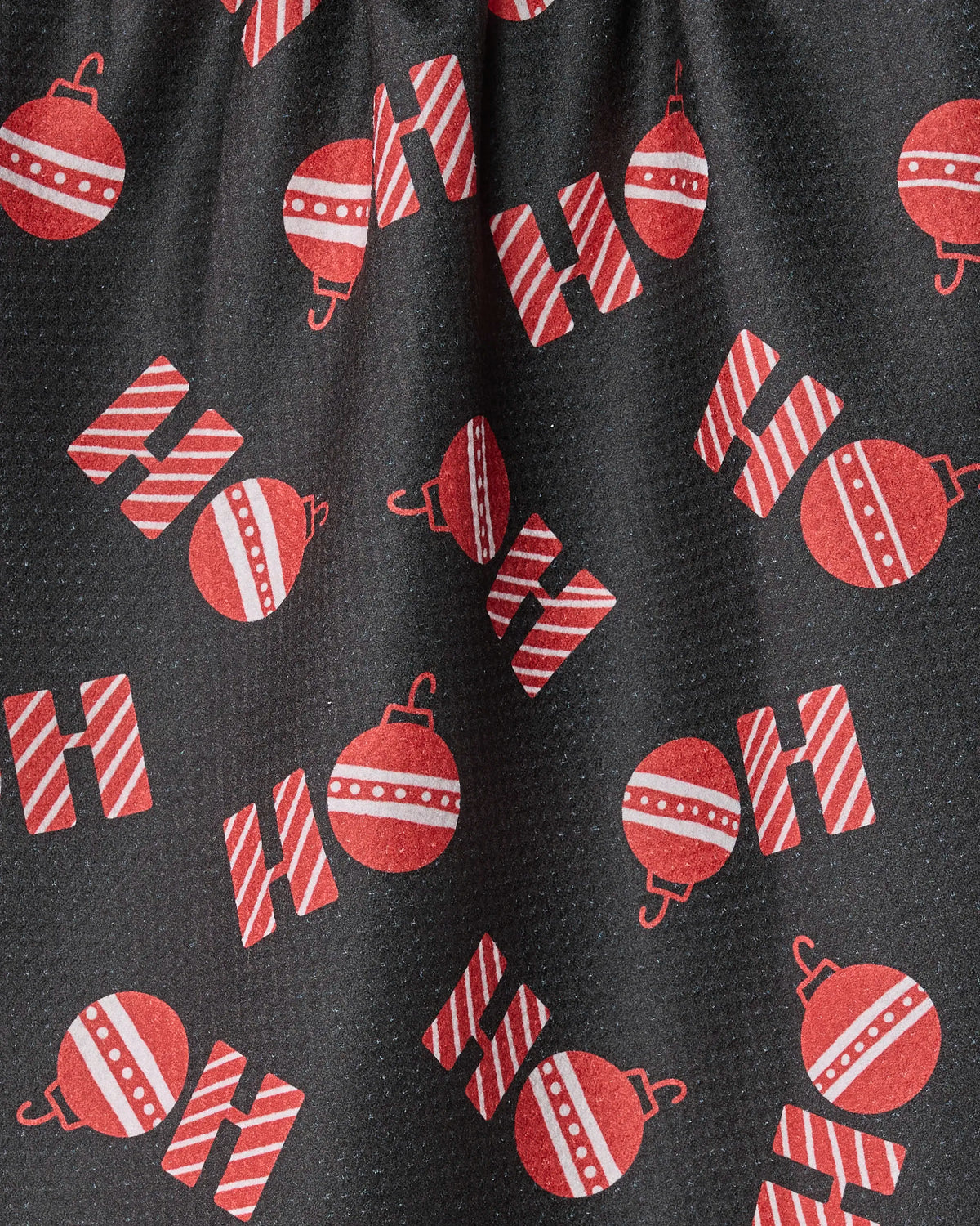 The Geometry Santa Greetings tea towel features black fabric adorned with red and white striped letters spelling “HO” and red Christmas ornaments with white stripes, evenly distributed across the surface. This ultra-absorbent towel brings festive flair and practical function to any holiday kitchen.